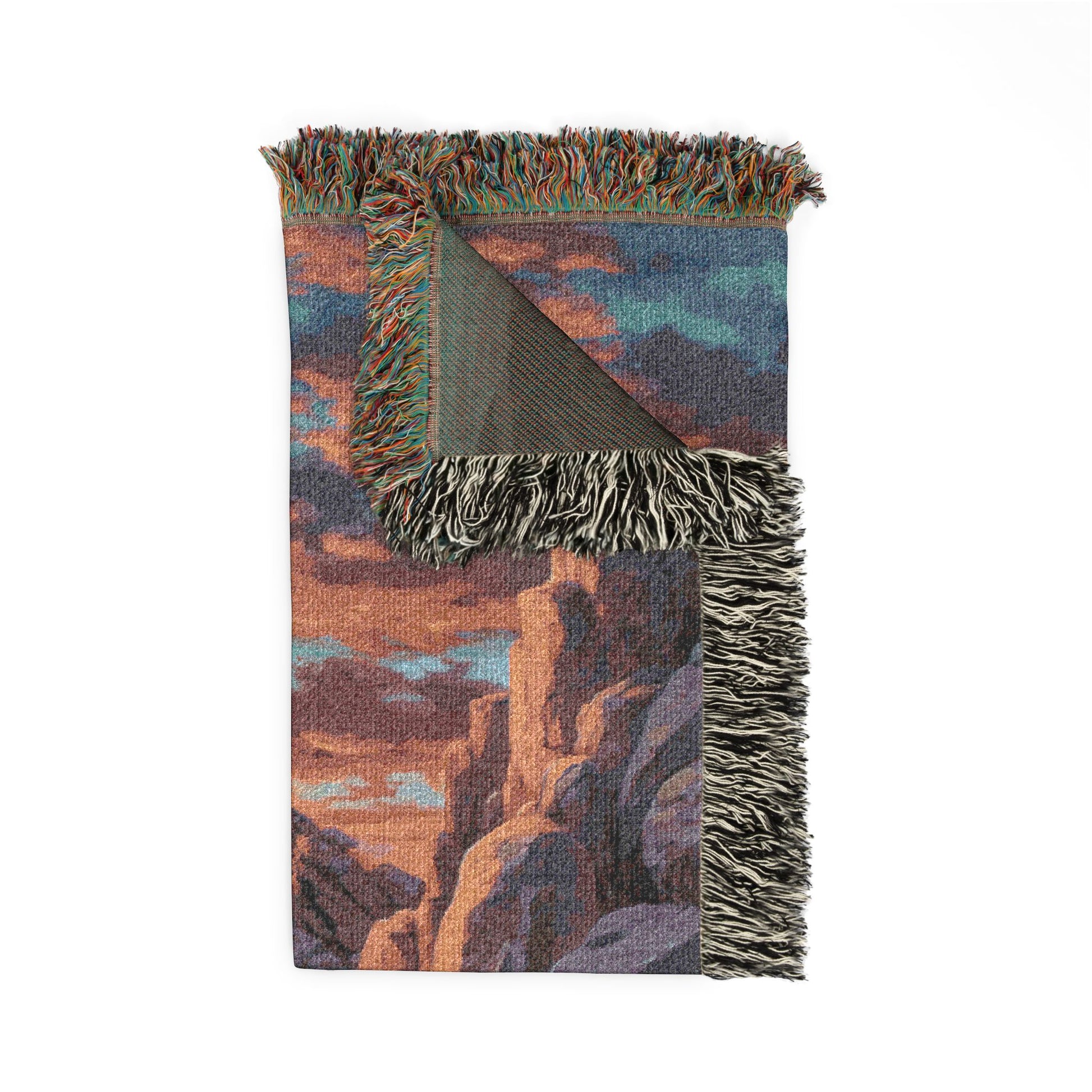 Woven blanket with landscape design and fringed edges on a white background