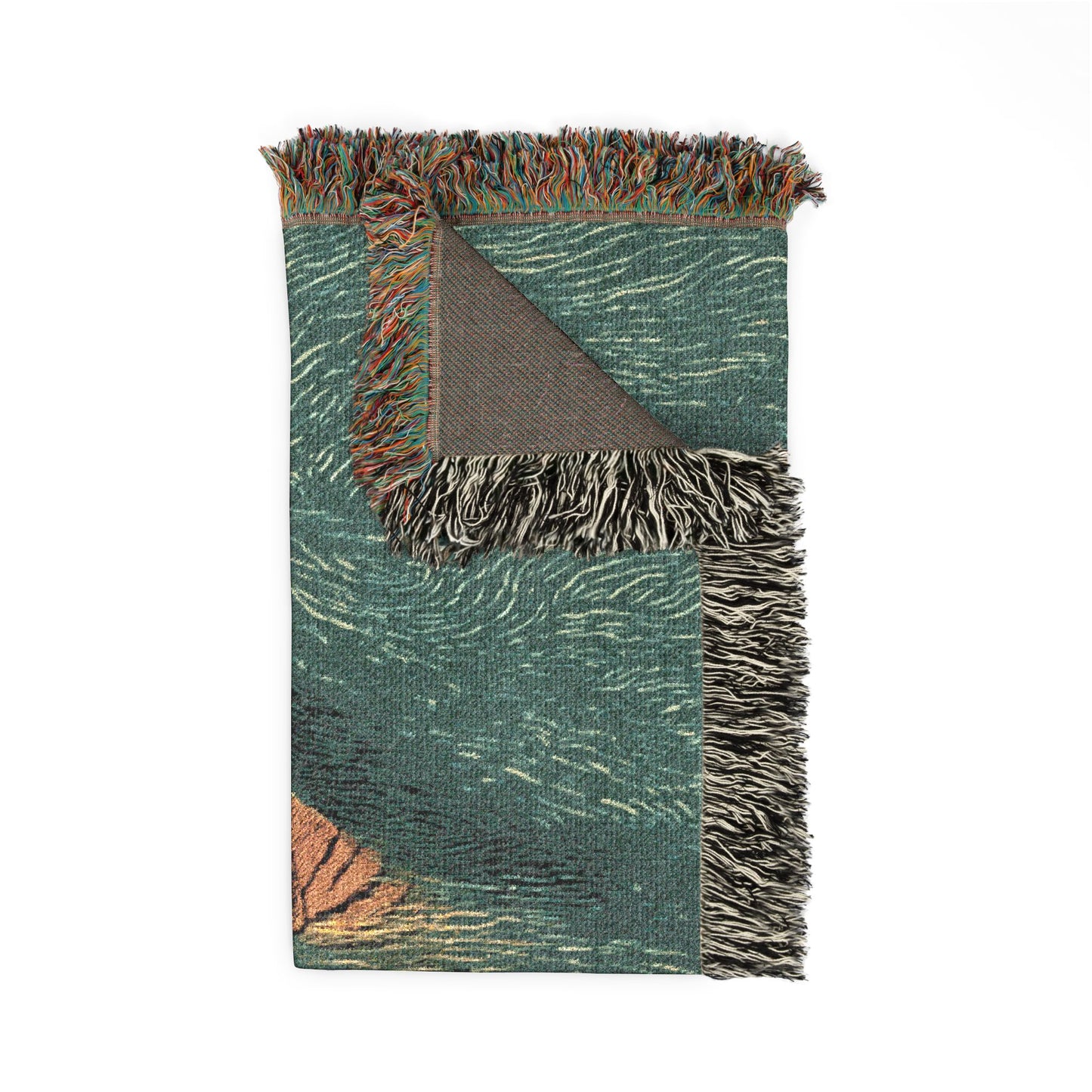 A woven throw blanket with fringe, featuring a textured teal green and white pattern with a folded corner revealing a brown underside, and a small orange accent in the lower left corner.