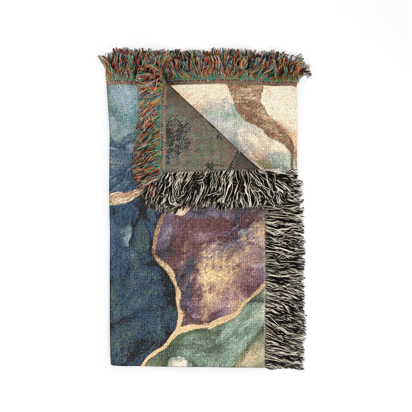 A rectangular woven throw blanket with fringed edges, featuring an abstract patchwork design in muted blue, green, purple, beige, and brown tones on a white background.