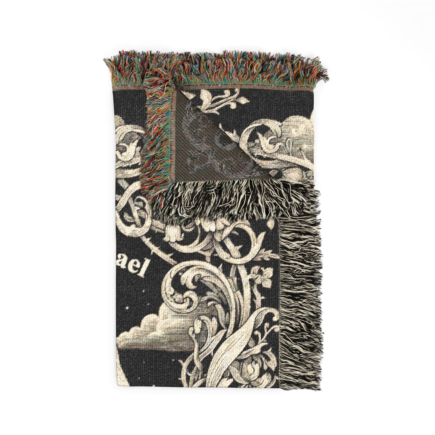A black woven throw blanket with cream-colored baroque scrollwork, clouds, and floral motifs, featuring multicolor fringe on all three sides.
