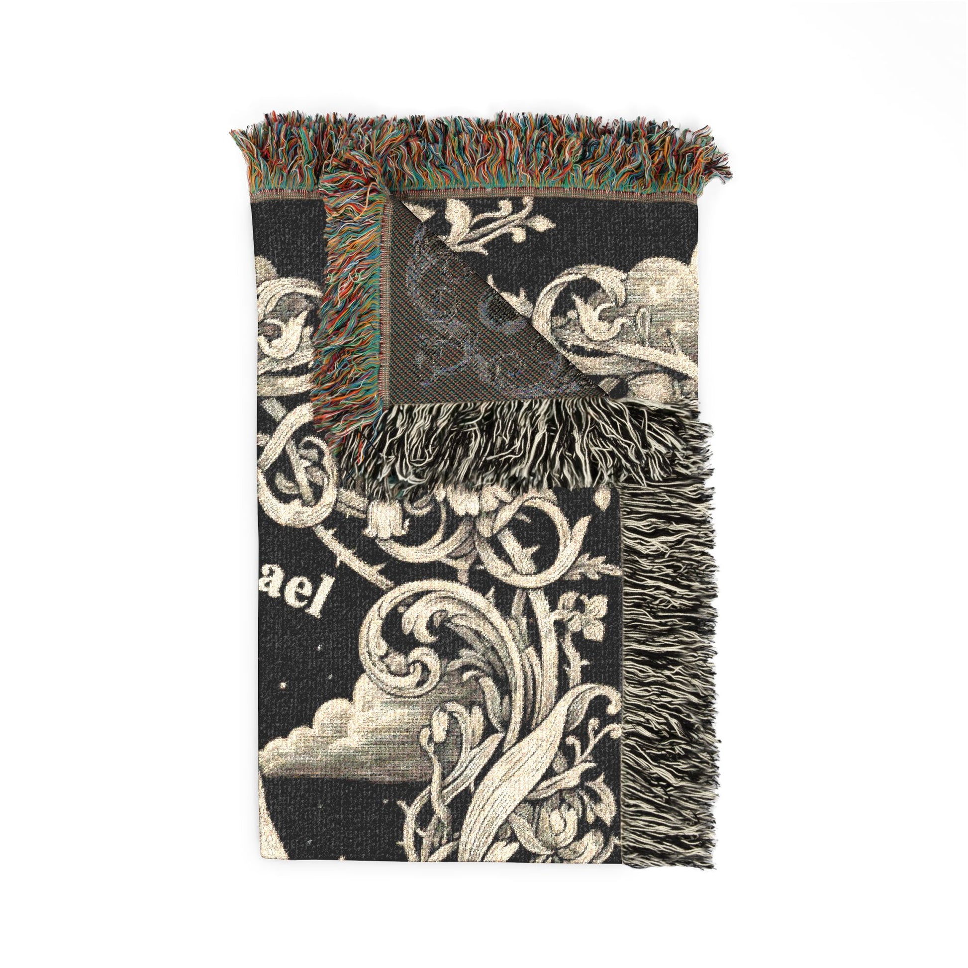 A black woven throw blanket with cream-colored baroque scrollwork, clouds, and floral motifs, featuring multicolor fringe on all three sides.
