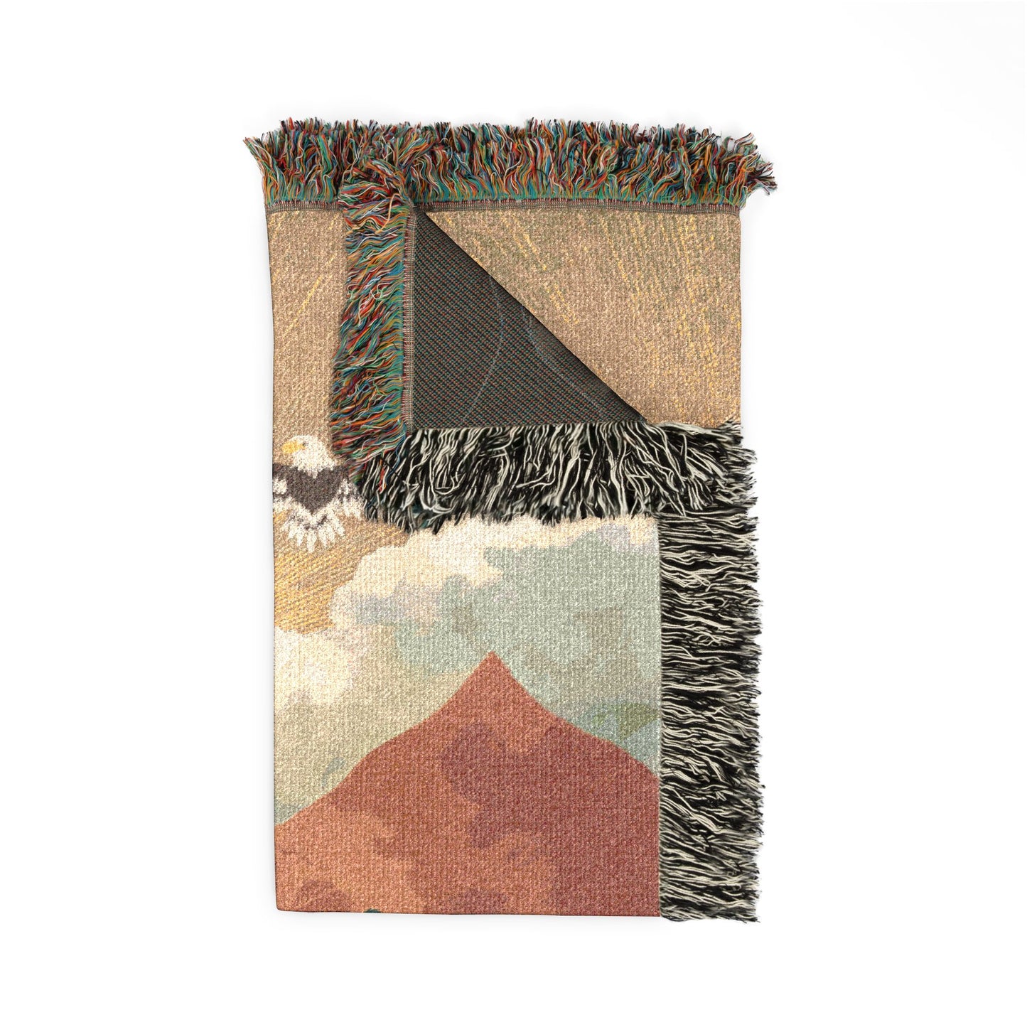 Woven blanket with mountain landscape design and fringed edge on a white background