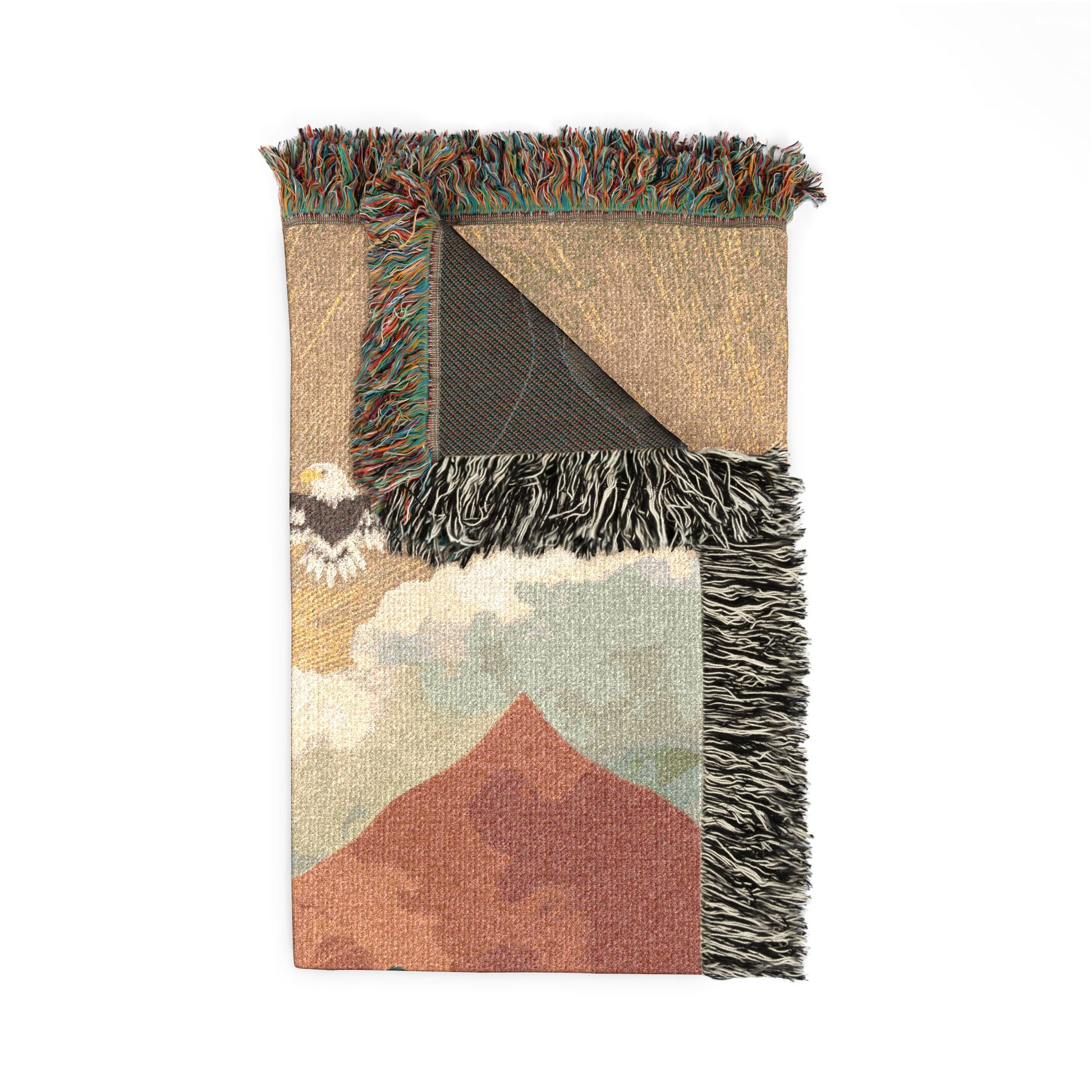 Woven blanket with mountain landscape design and fringed edge on a white background