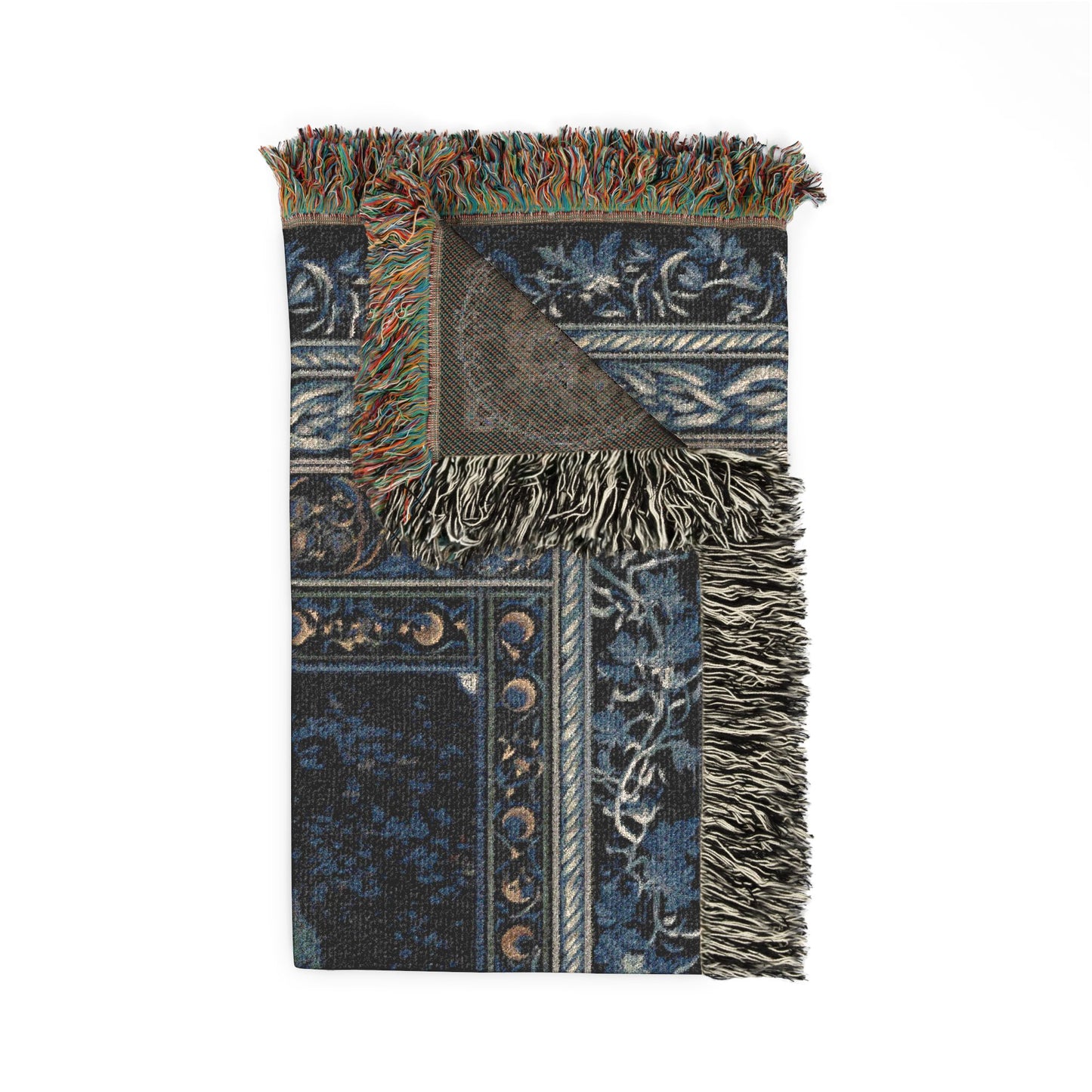 A folded patterned throw blanket with fringed edges, shown on a plain white background. The blanket features a dark navy blue and black base with traditional ornamental patterns in beige, brown, and muted green, and has a triangular section turned over to show the reverse side.