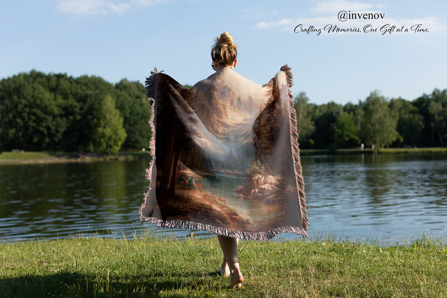 Person holding a painting art blanket by a lake with trees in the background