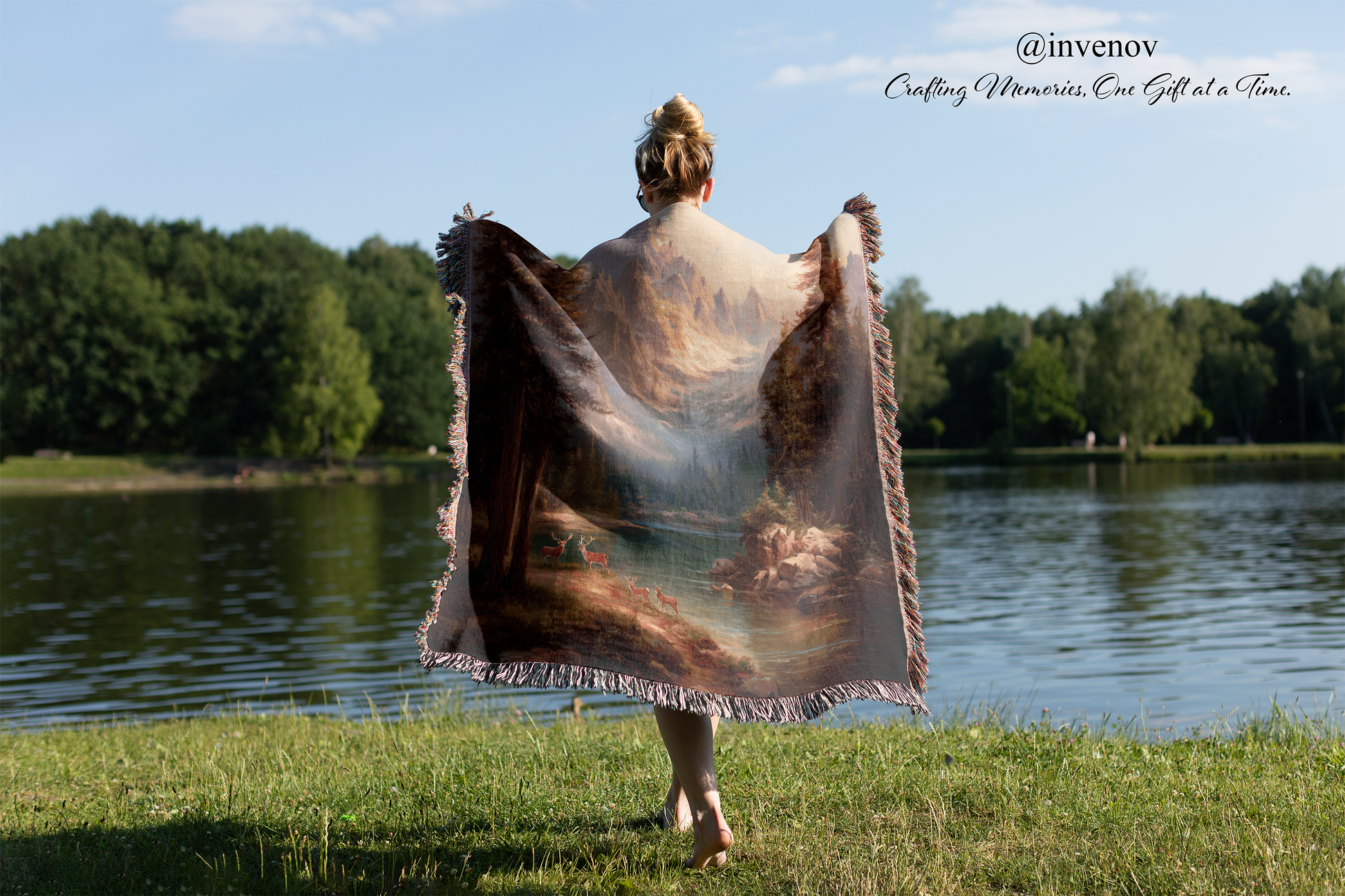Person holding a painting art blanket by a lake with trees in the background