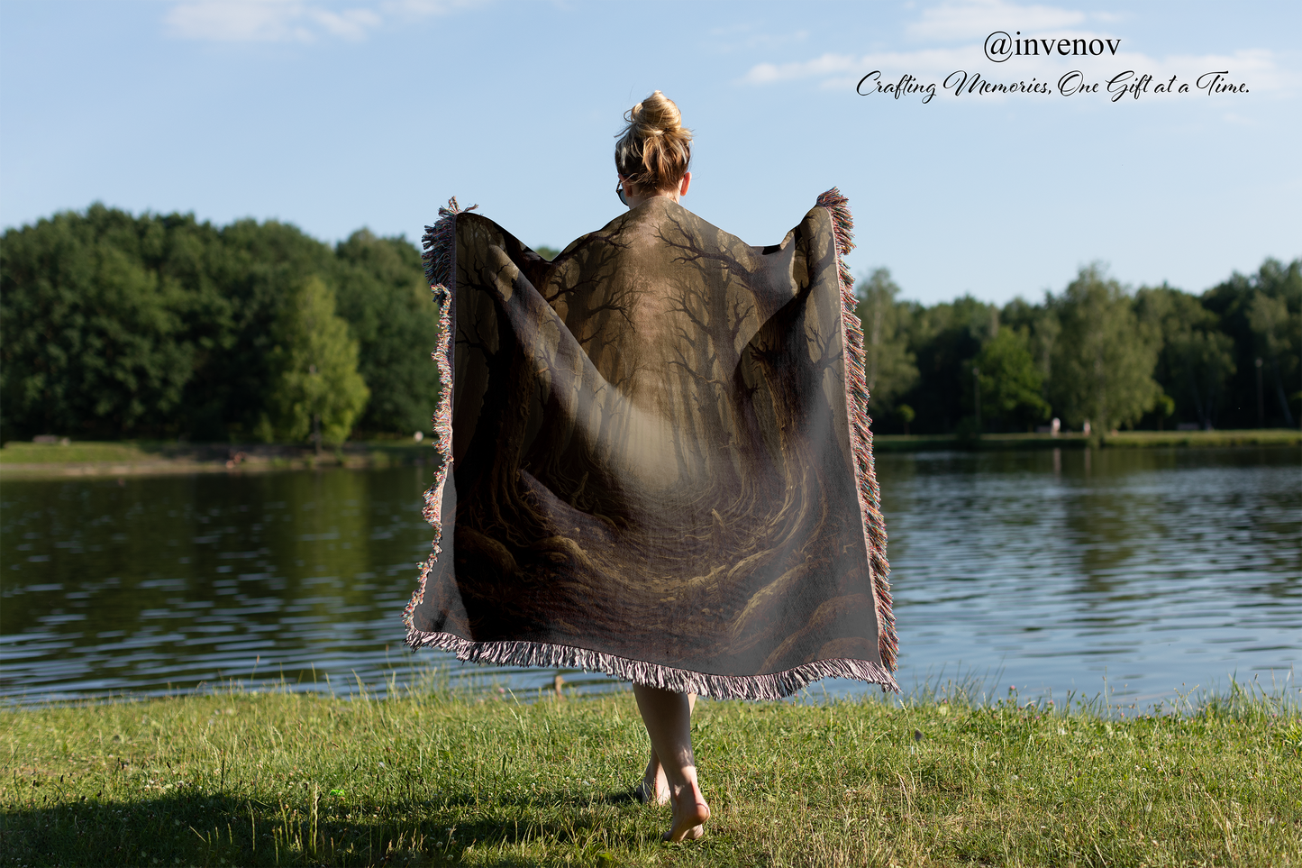 Person holding a large blanket by a lake with trees in the background