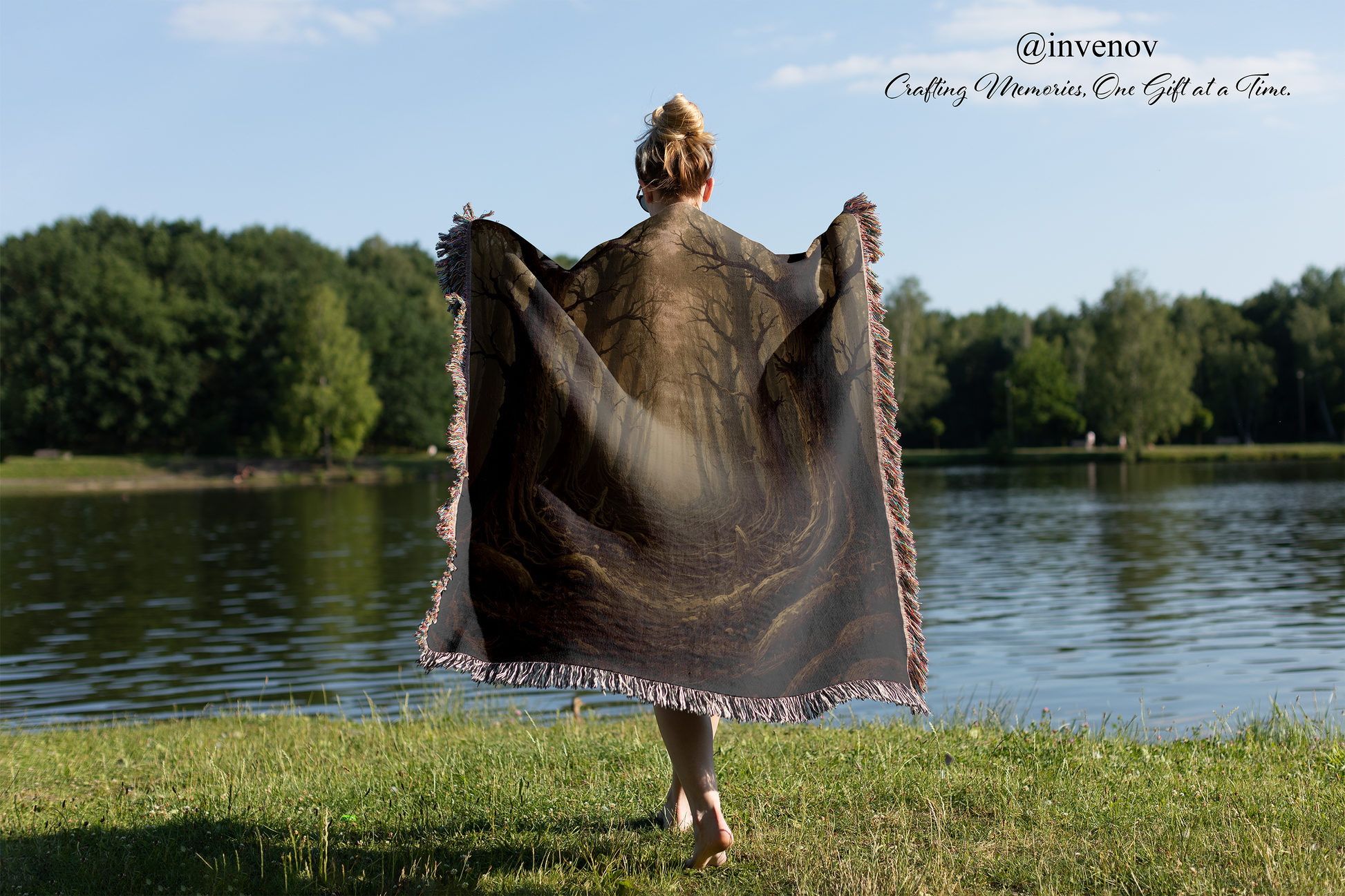 Person holding a large blanket by a lake with trees in the background