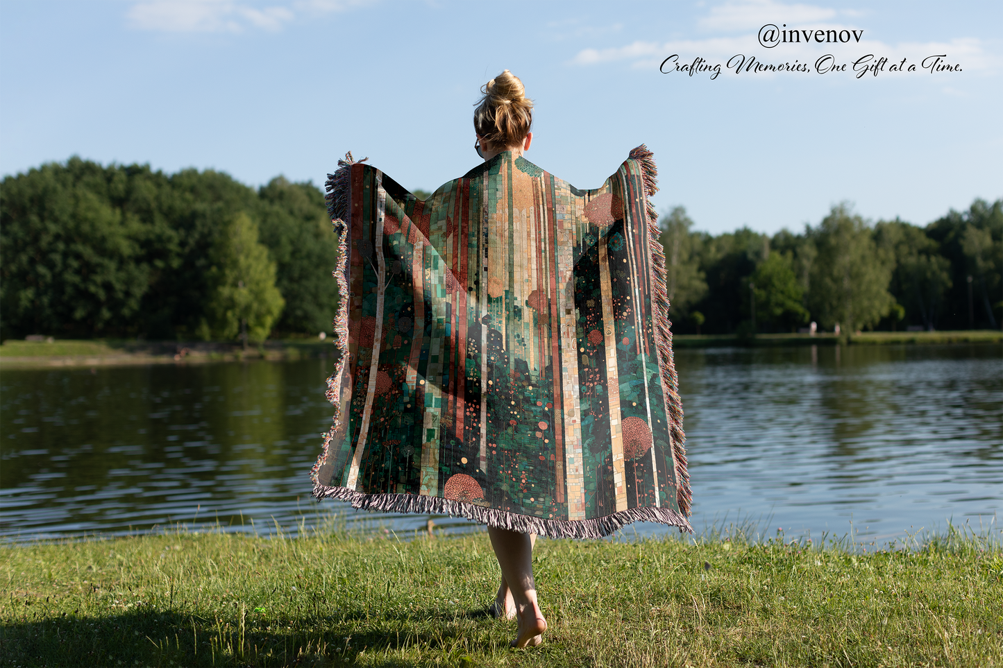 Person holding a colorful patterned blanket by a lake with trees in the background