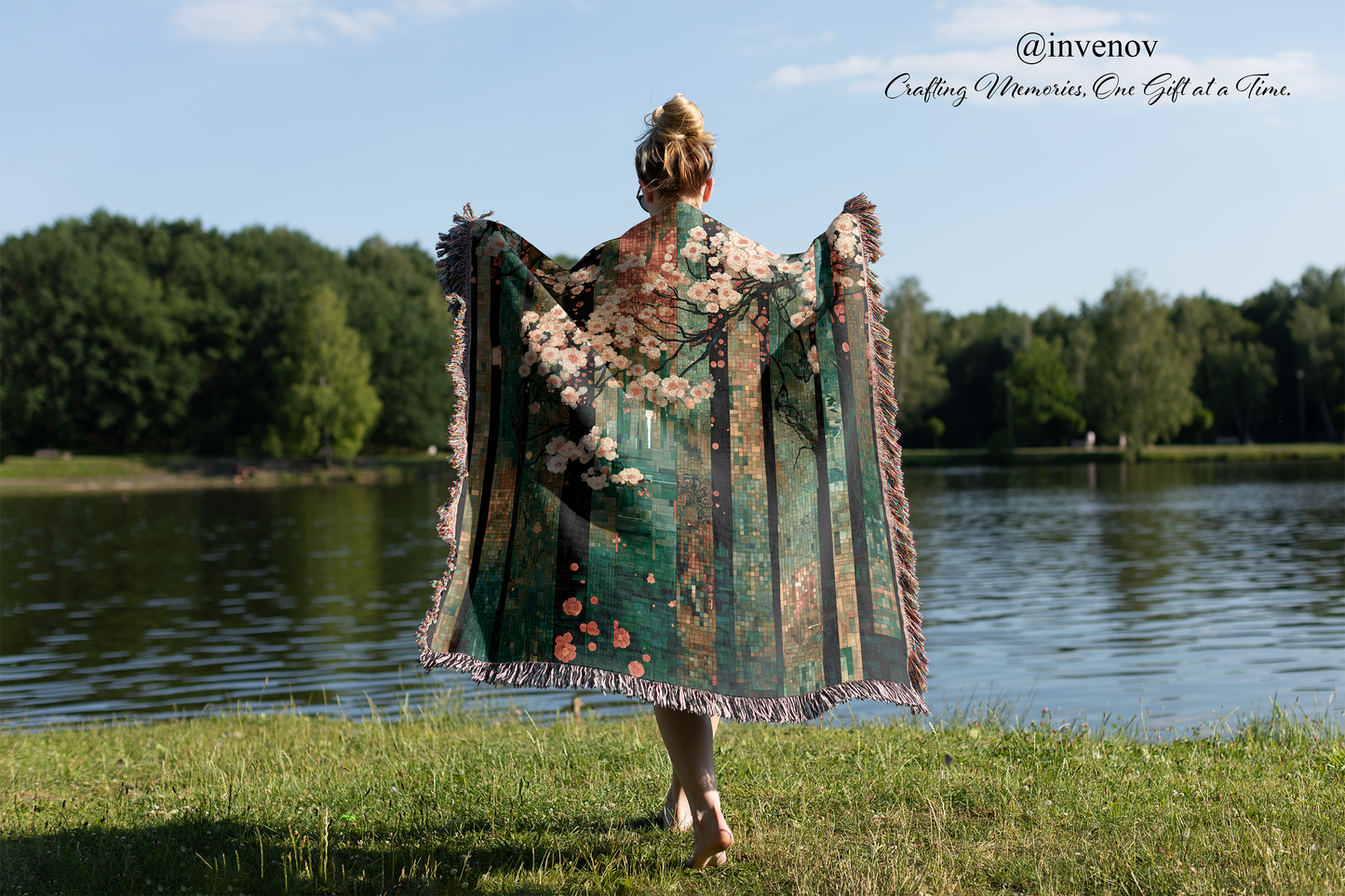 Person holding a floral-patterned blanket by a lake with trees in the background