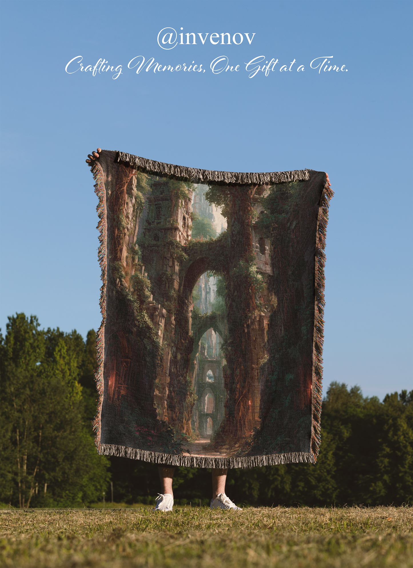 Person holding a woven blanket with a scenic design of ruins against a blue sky.