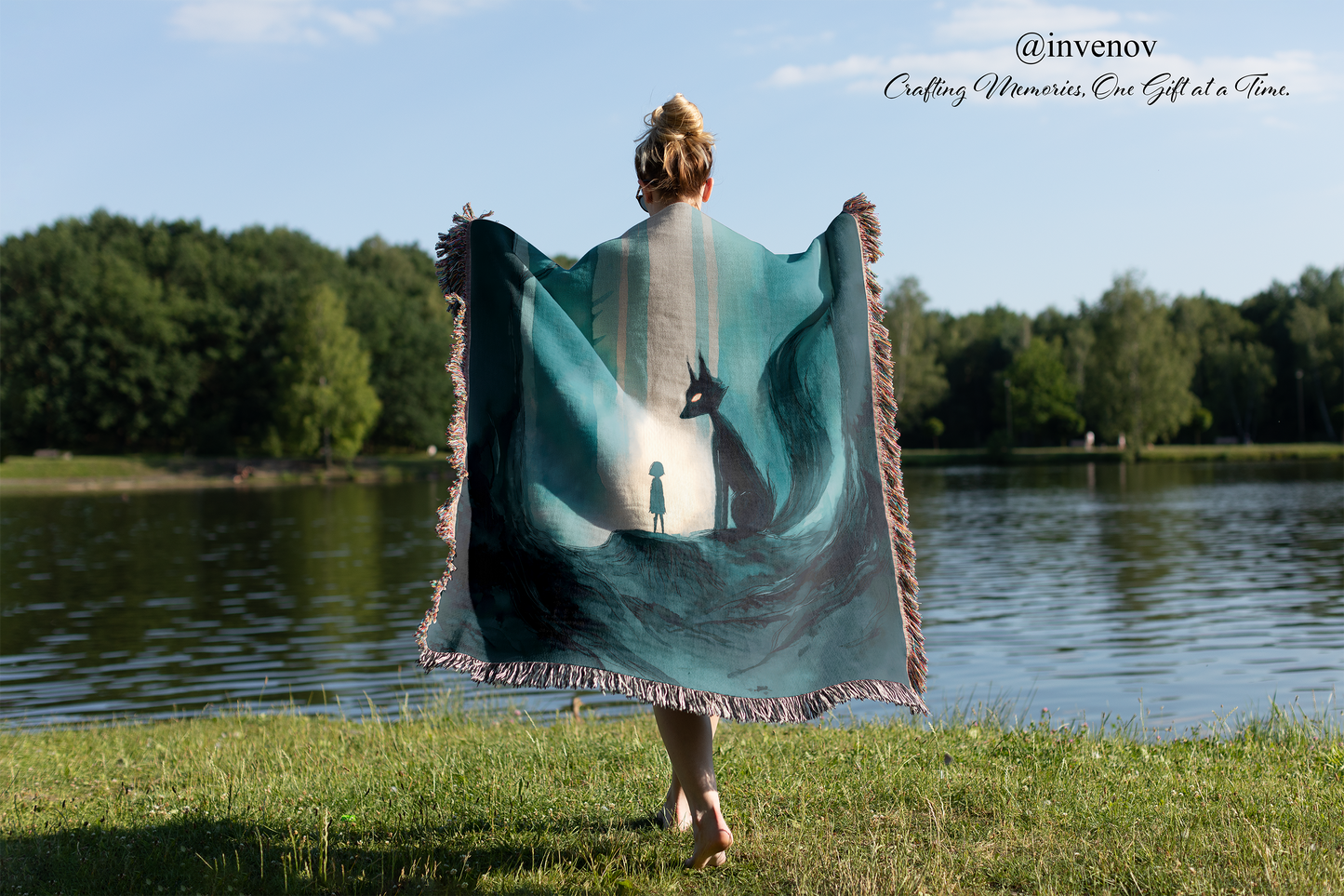 Person holding a large woven blanket with a nature design by a lake
