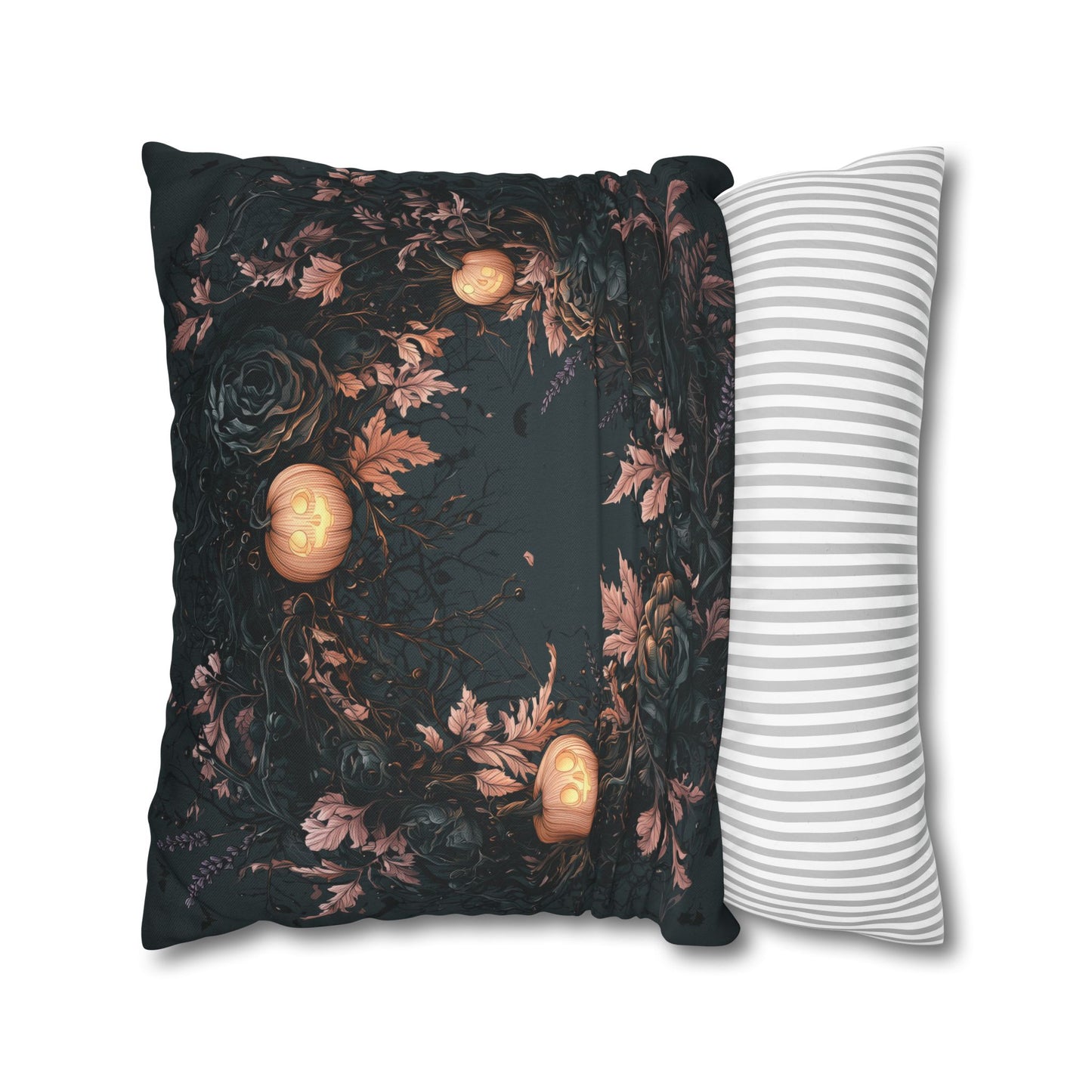 A decorative throw pillow with a black background, featuring a dark floral pattern and three glowing jack-o'-lantern motifs, shown next to a white pillow with thin gray stripes on a white background.