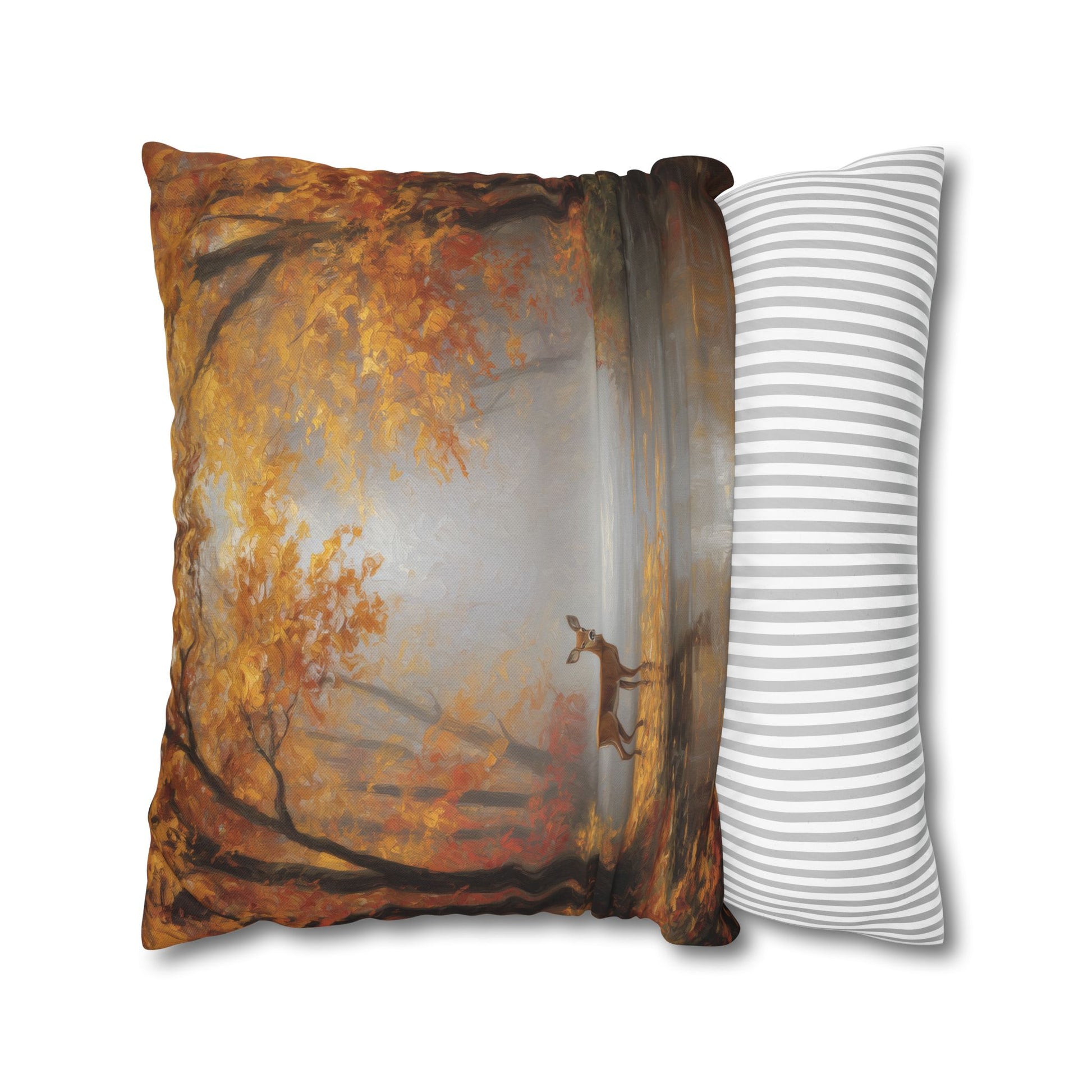 A square decorative throw pillow featuring a printed autumn forest scene with orange and brown trees, shown next to a white pillow with thin gray horizontal stripes on a plain white background.