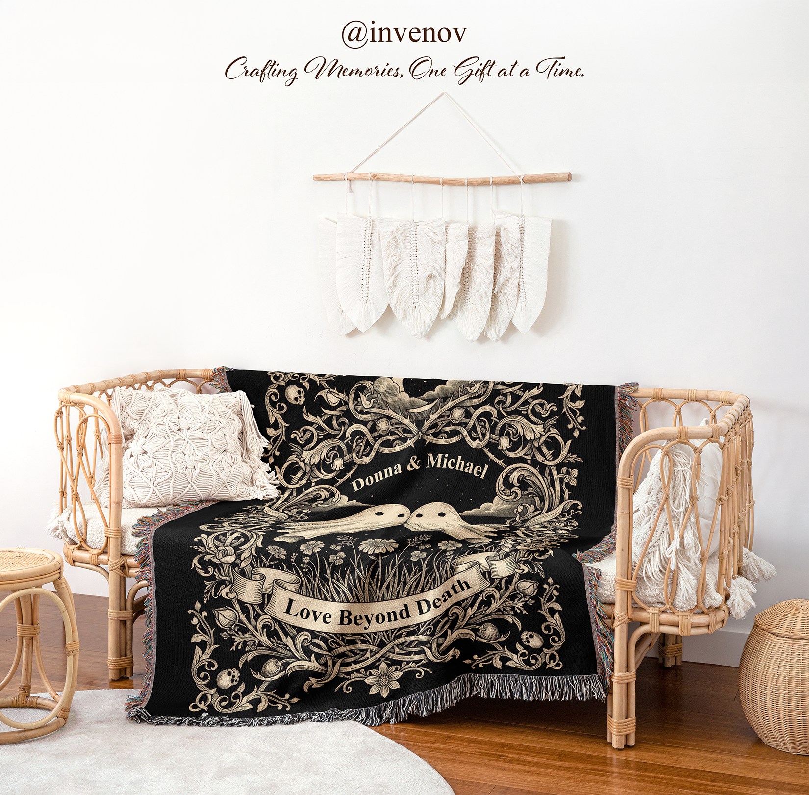 A black throw blanket with cream-colored gothic-style floral scrollwork, a pair of ghost, draped over a rattan daybed in a styled room setting.