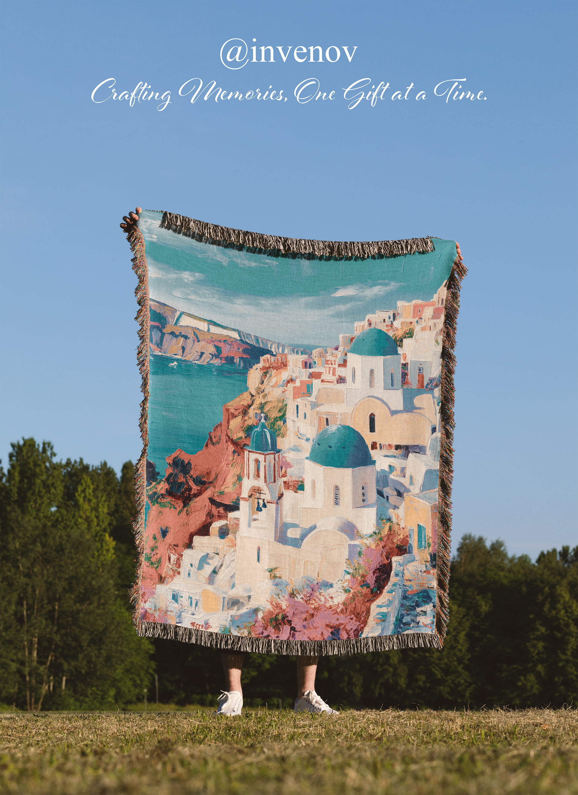 Person holding a colorful blanket with a scenic design against a clear blue sky.
