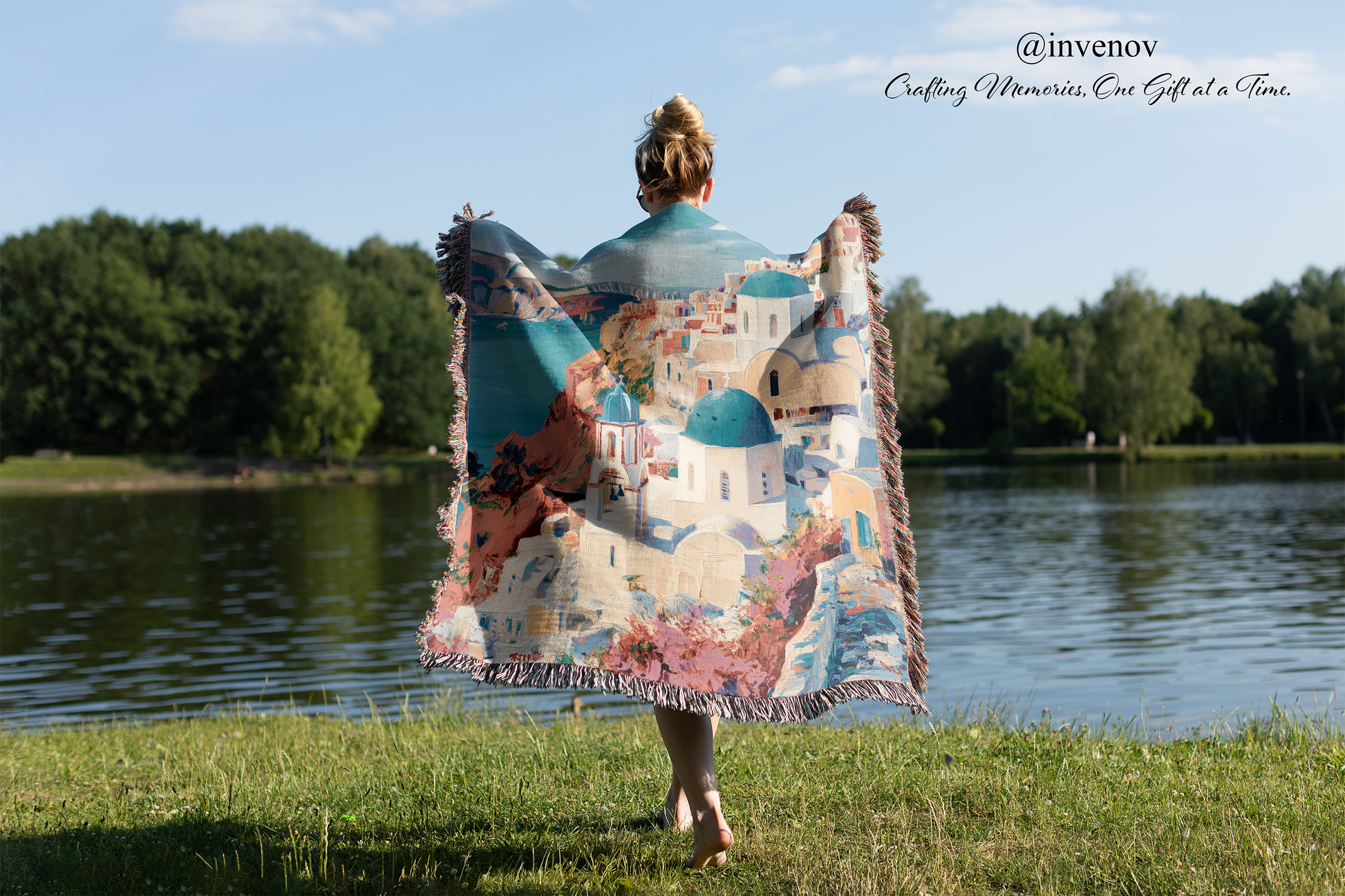 Person holding a colorful blanket with a scenic design by a lake