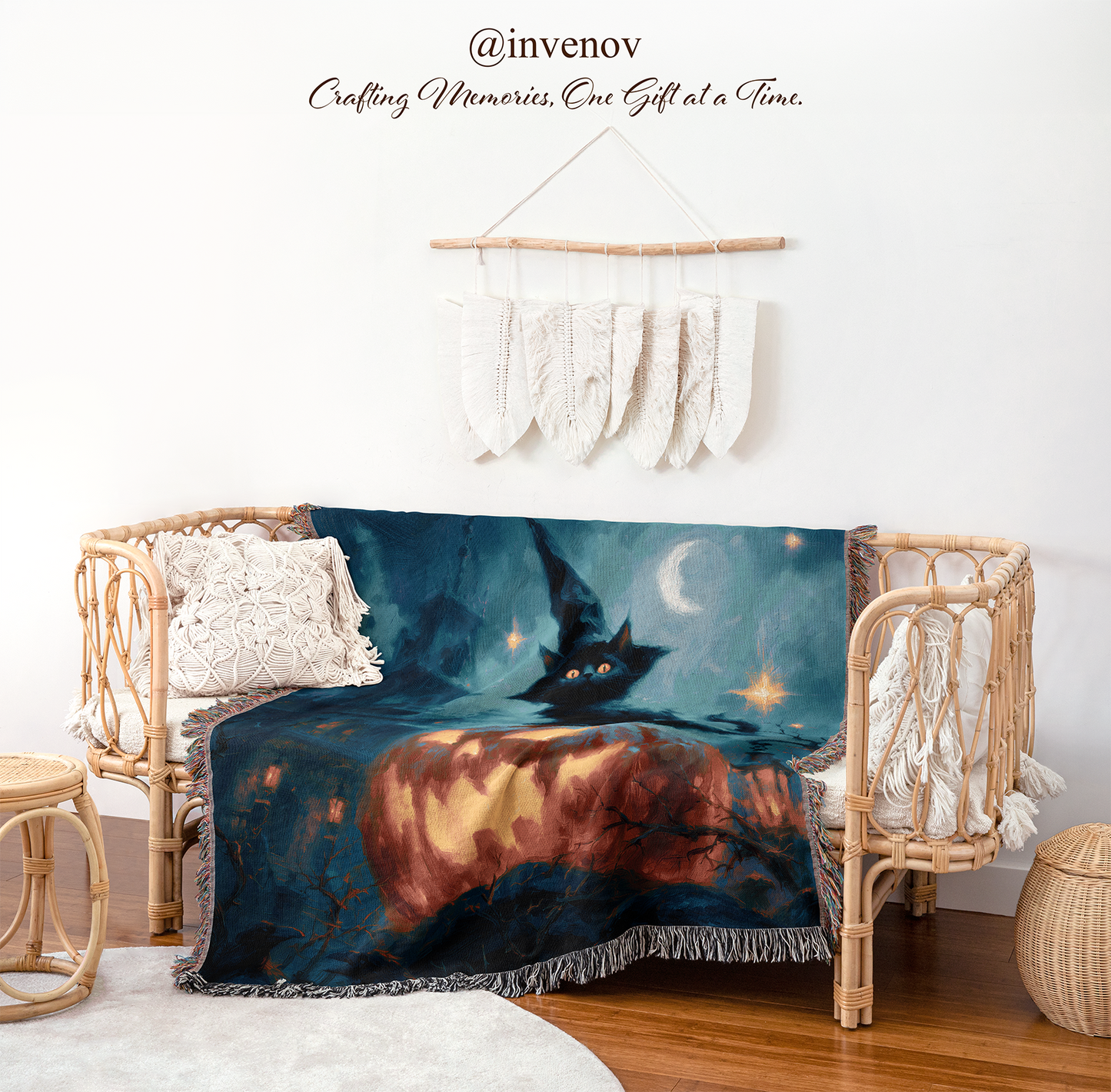 A dark fantasy-themed throw blanket featuring a black cat in a witch hat under a crescent moon, draped over a rattan daybed in a styled room setting.