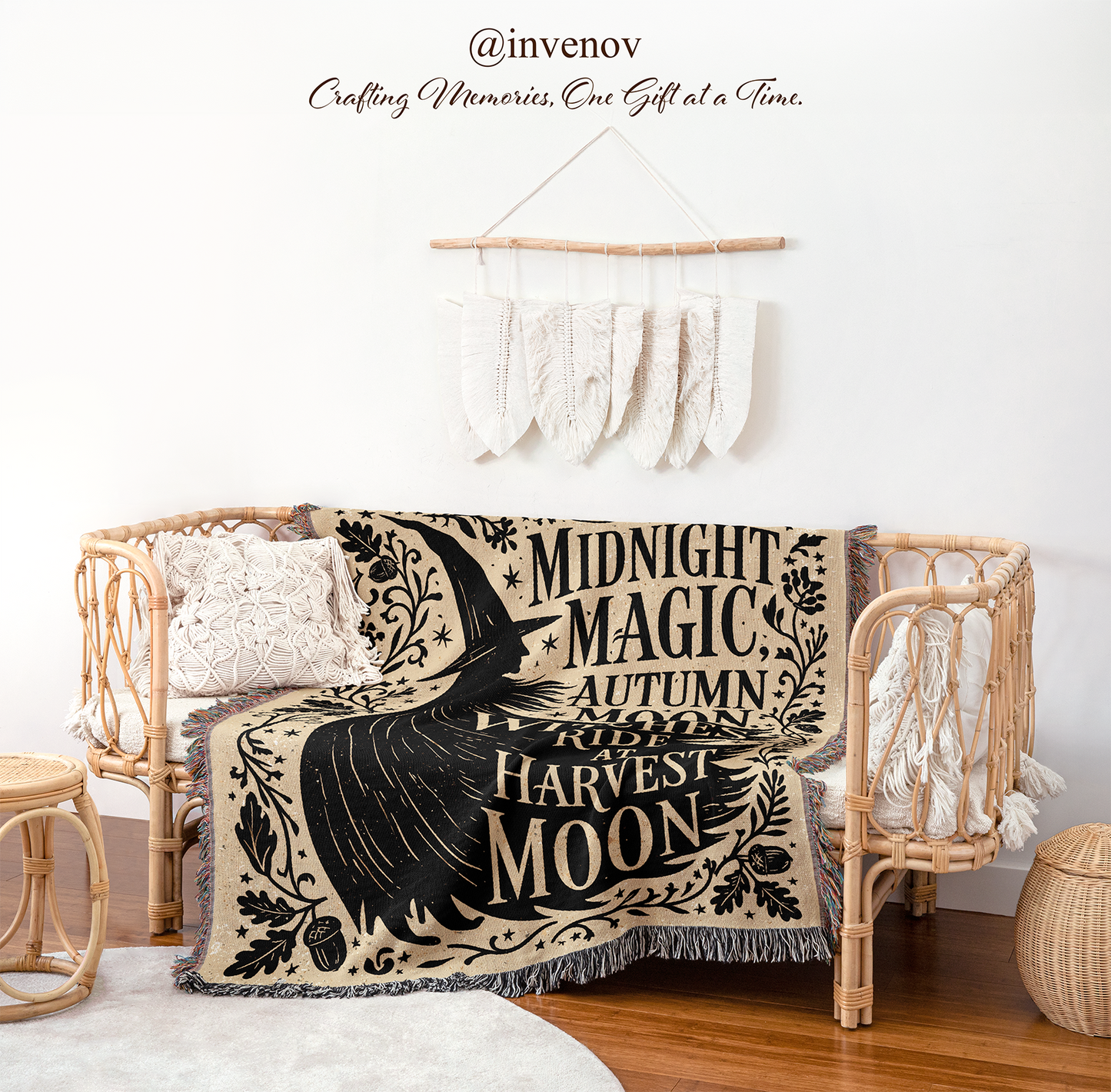 A bohemian-style woven throw blanket draped over a rattan daybed in a styled room. The blanket features a black bird and text reading 'Midnight Magic, Autumn Rituals, Roots, Harvest, Moon' on a beige background.