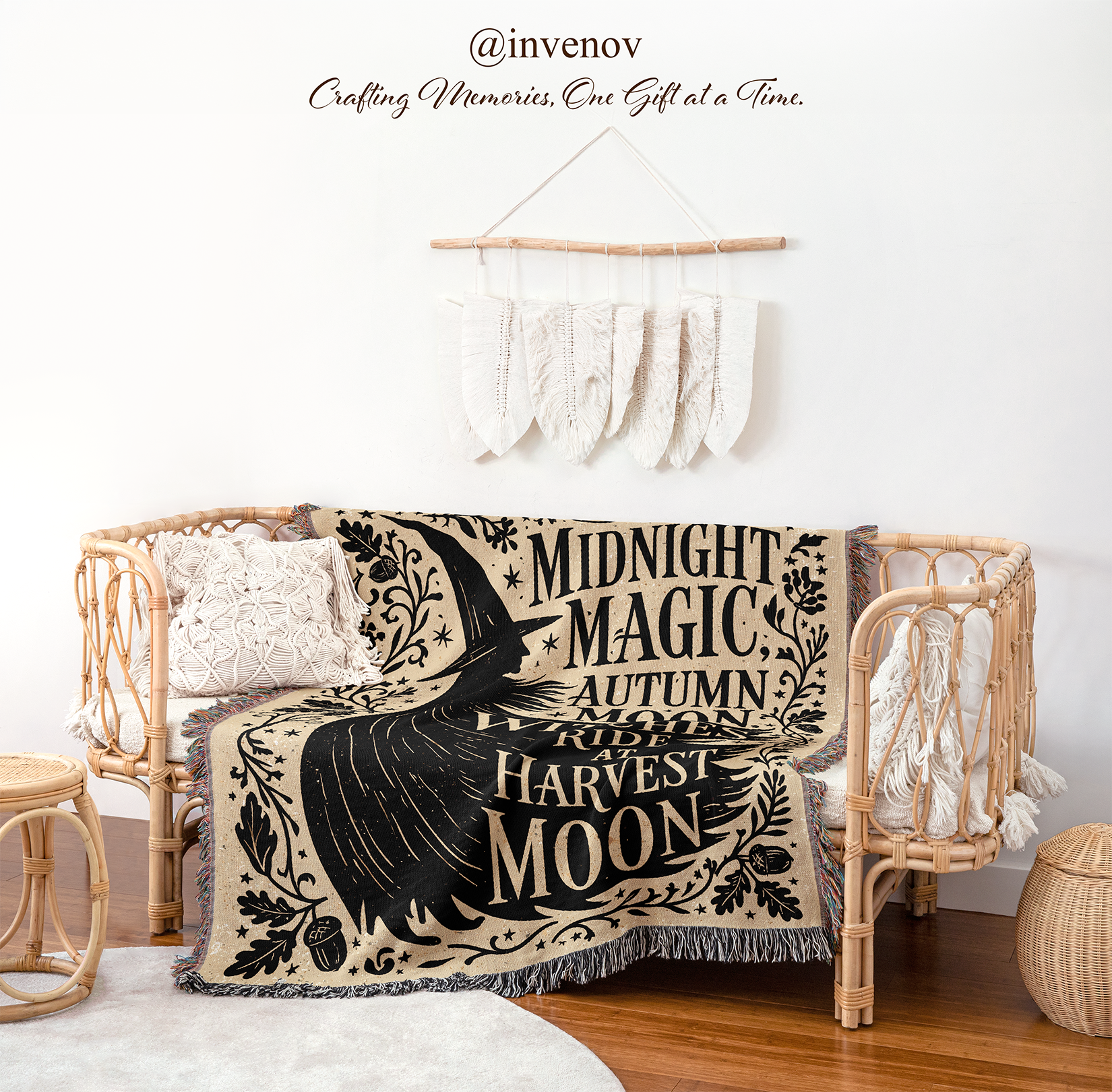 A bohemian-style woven throw blanket draped over a rattan daybed in a styled room. The blanket features a black bird and text reading 'Midnight Magic, Autumn Rituals, Roots, Harvest, Moon' on a beige background.