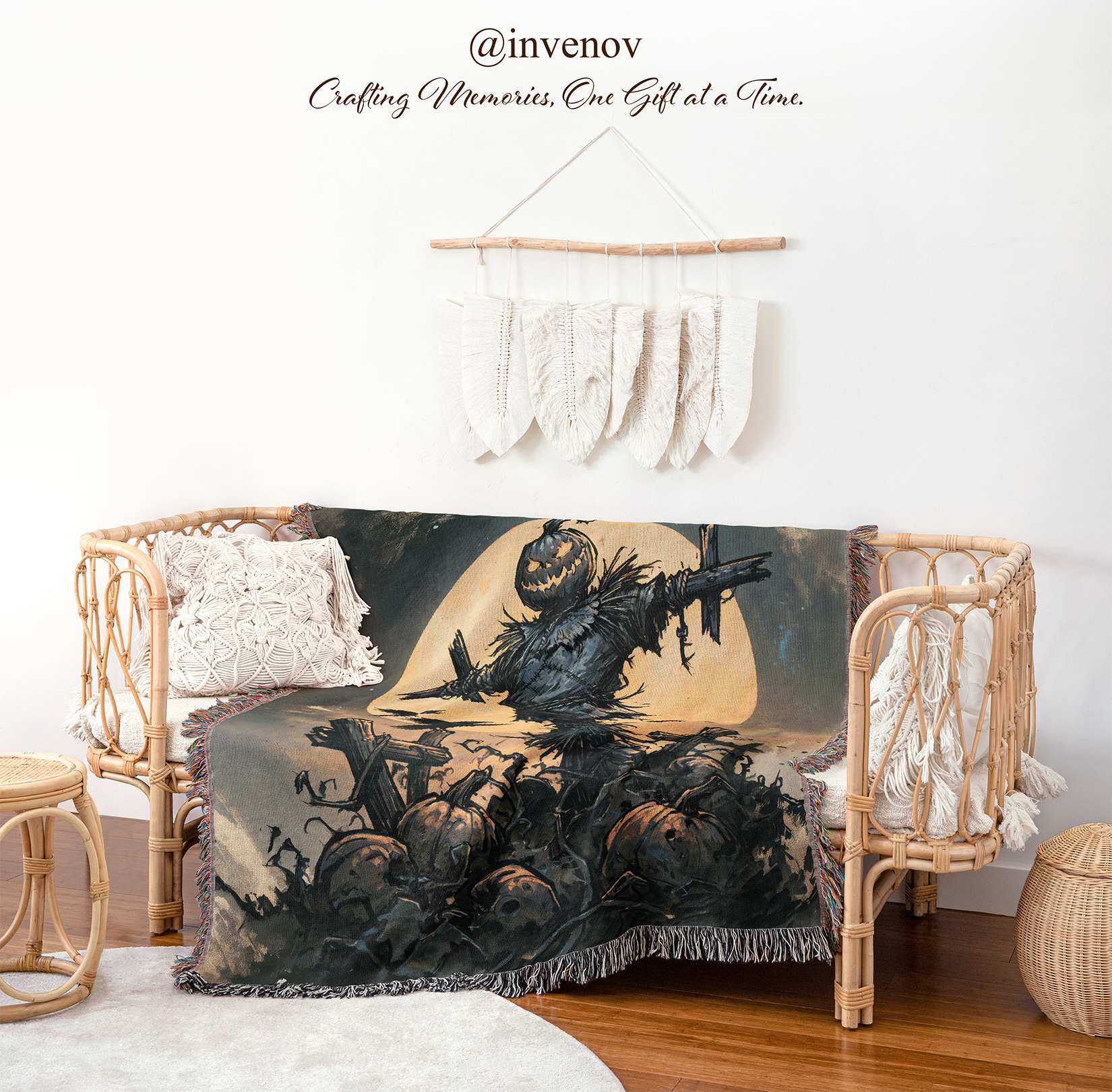 A Halloween-themed throw blanket draped over a rattan daybed in a styled room. The blanket features a dark illustration of a scarecrow, pumpkins, bats, and a large pale moon.