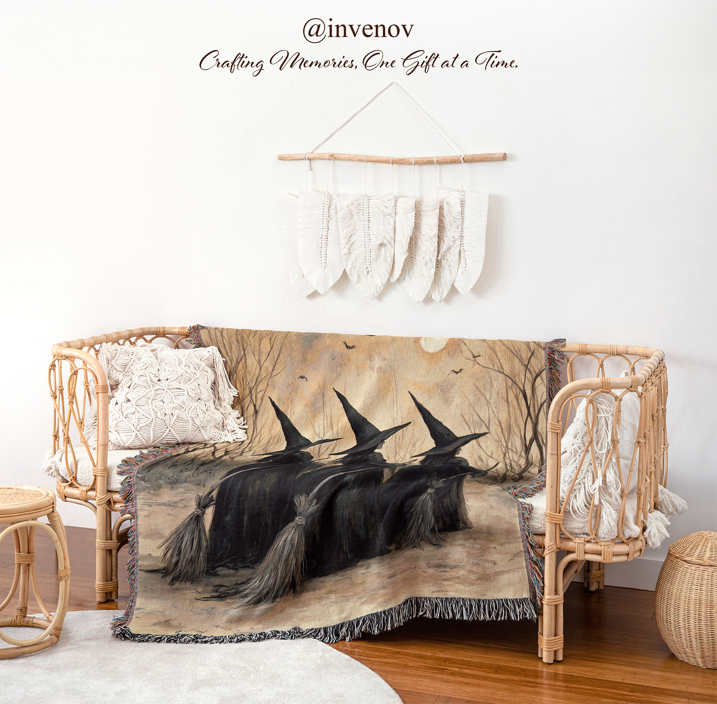 A woven throw blanket featuring a spooky illustration of three witches riding broomsticks under a full moon, draped over a rattan daybed in a styled room setting.