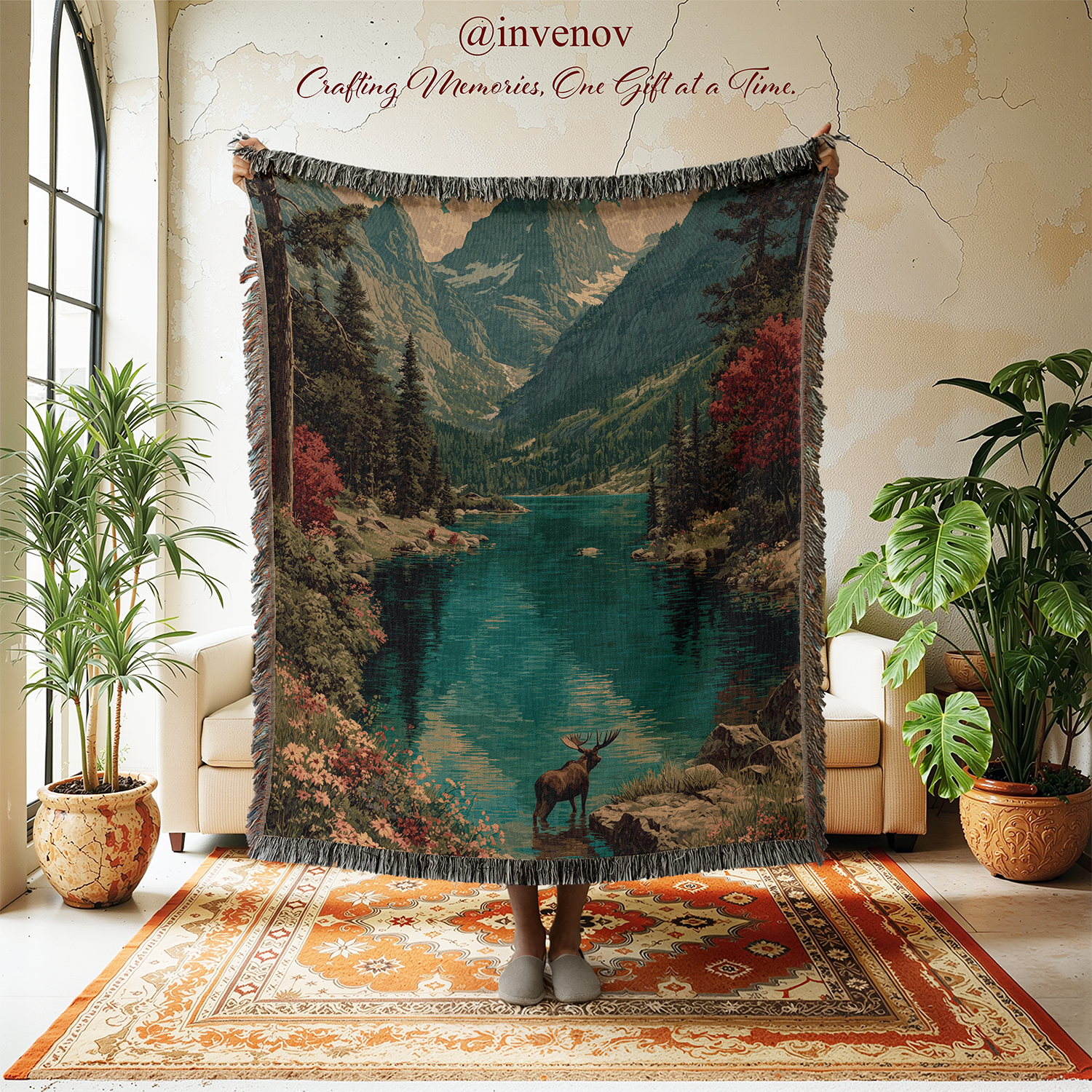 Person holding a scenic blanket with mountains and a lake in a room with plants and a rug.