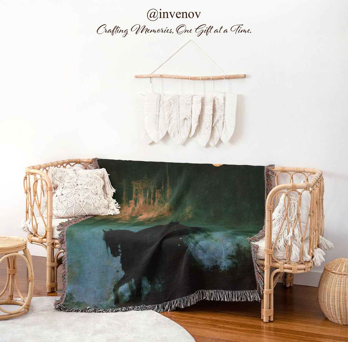 A woven throw blanket with a dark forest scene and a black horse is draped over a rattan daybed in a styled room setting. The scene includes a macrame wall hanging, wooden floor, and decorative pillows.