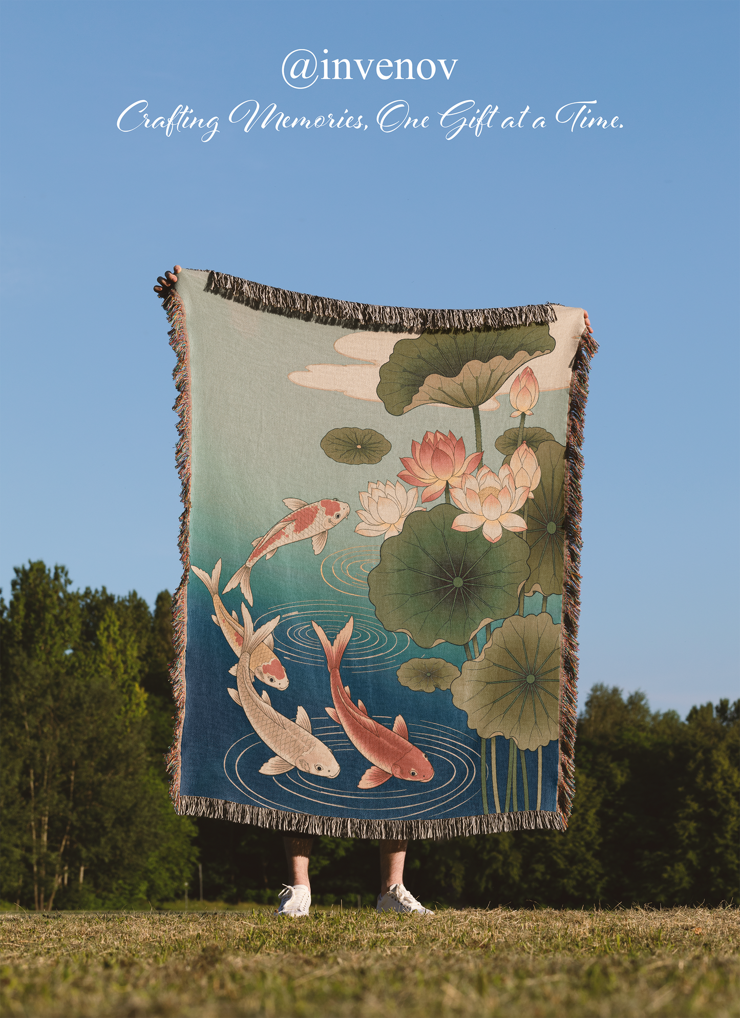 Person holding a decorative blanket with koi fish and lotus designs against a blue sky.