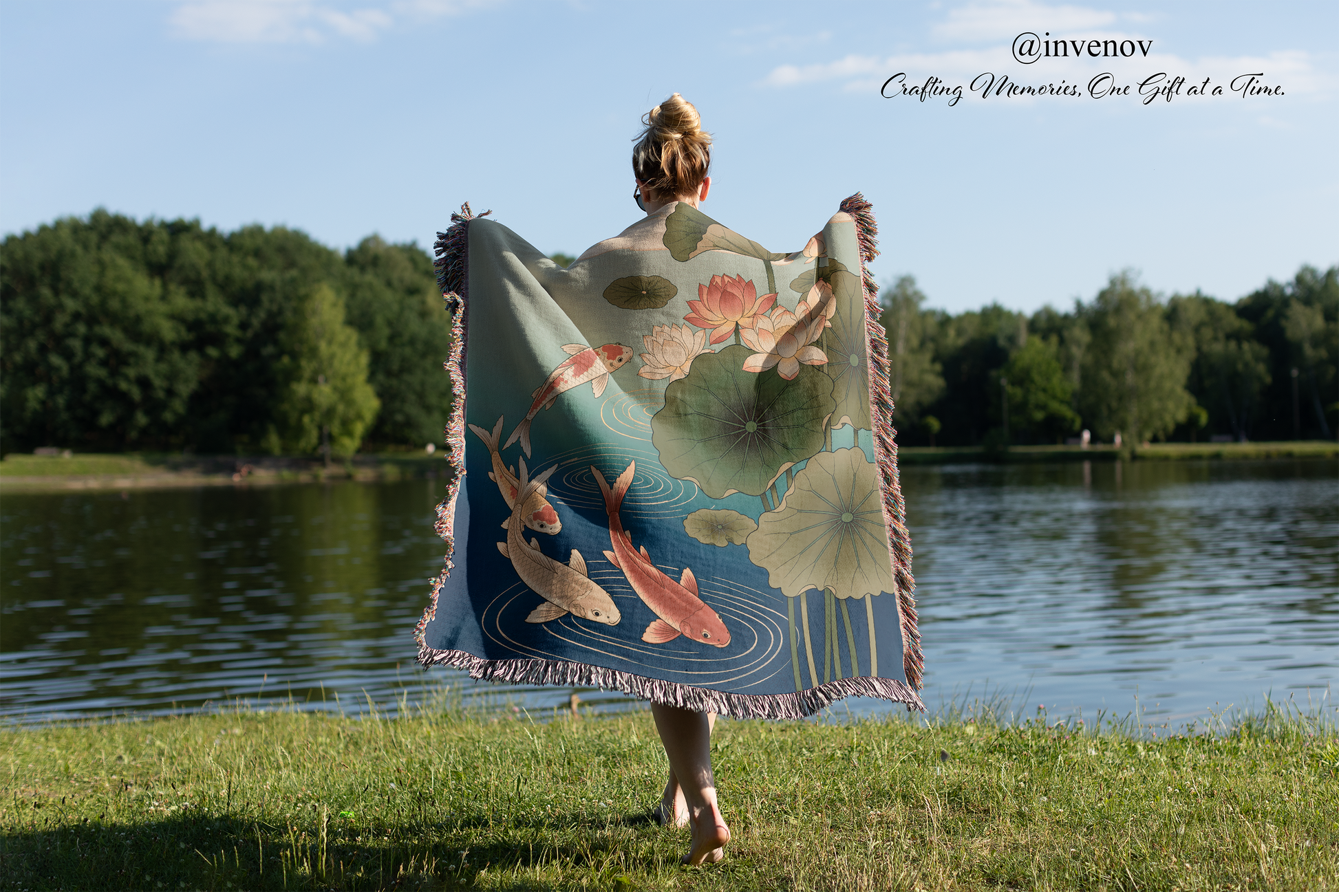 Person holding a floral-patterned blanket by a lake with trees in the background