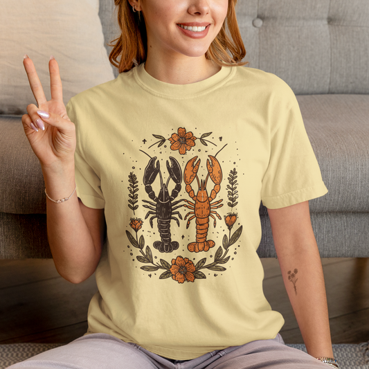 Person wearing a light yellow t-shirt with a lobster design, sitting on a couch.