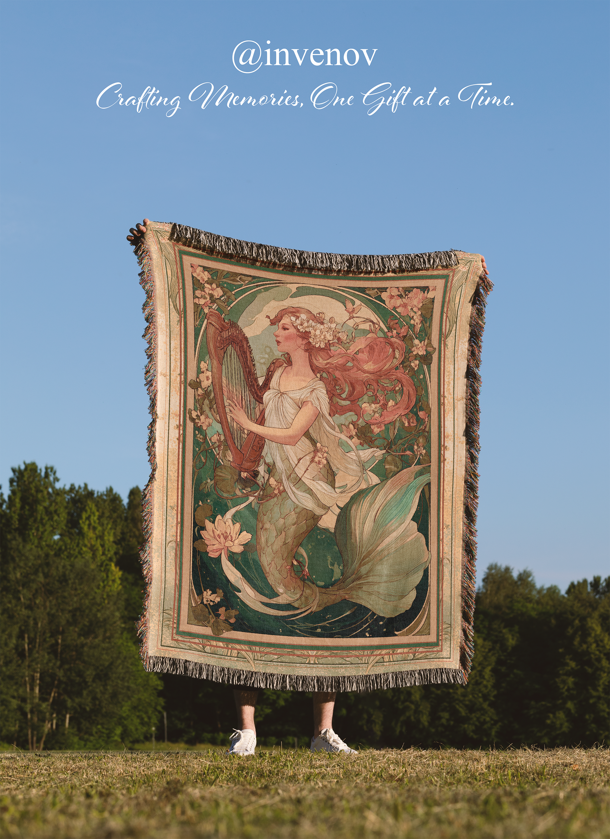 Person holding a tapestry with a mermaid design against a blue sky and trees.