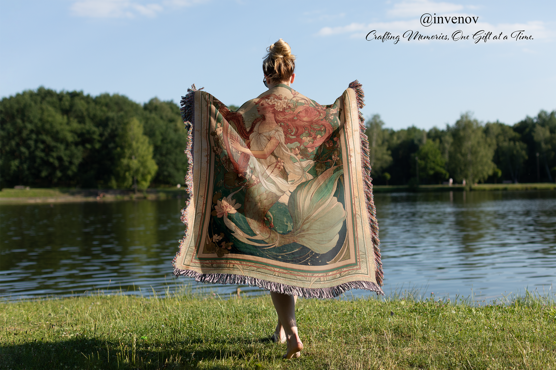 Person holding a decorative tapestry by a lake with trees in the background