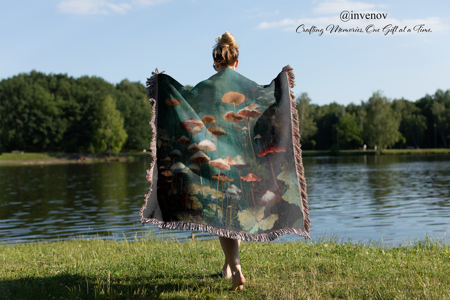 Person holding a colorful mushroom graphic blanket with floral design by a lake