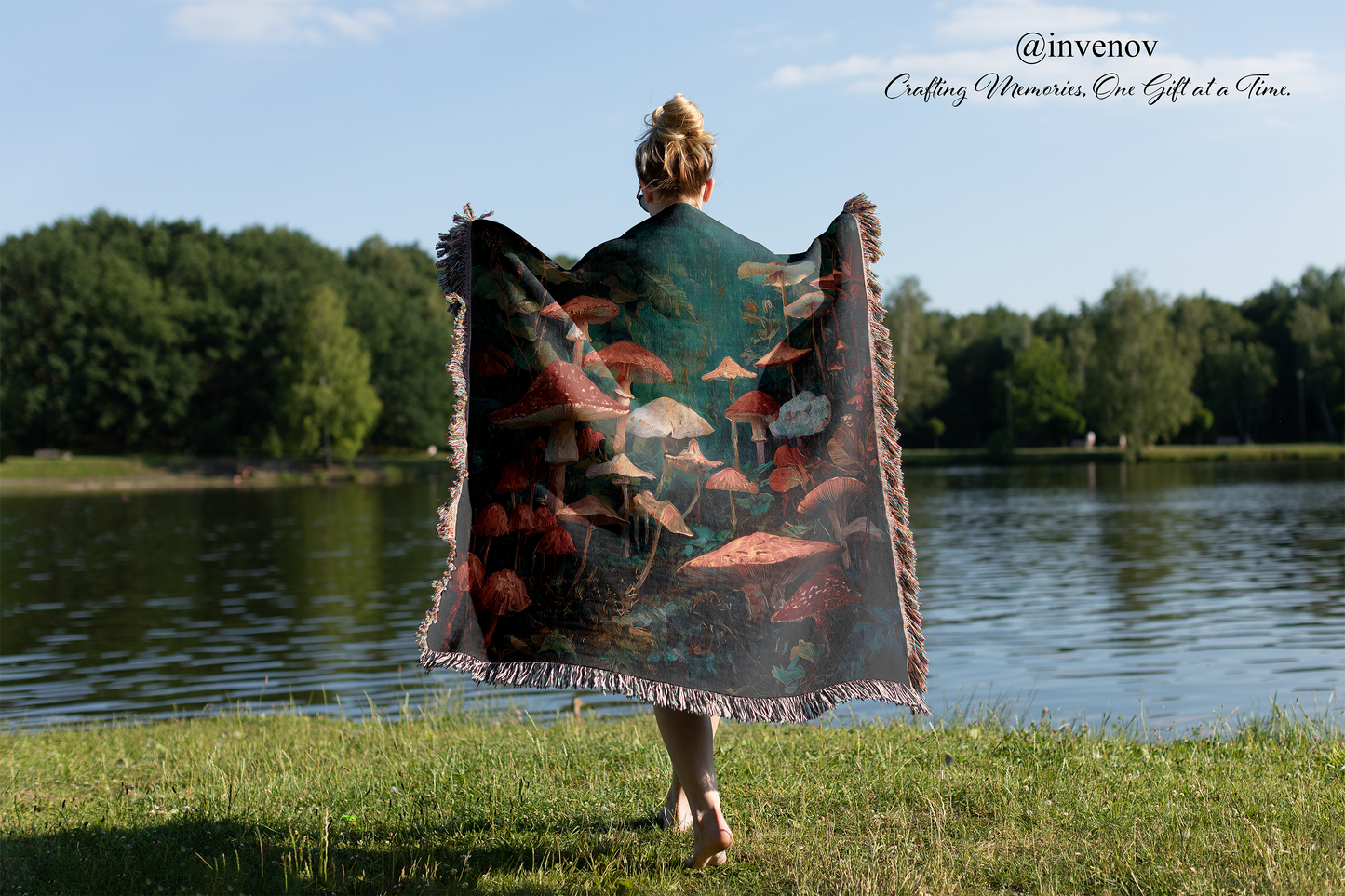 Person holding a colorful blanket with nature design by a lake