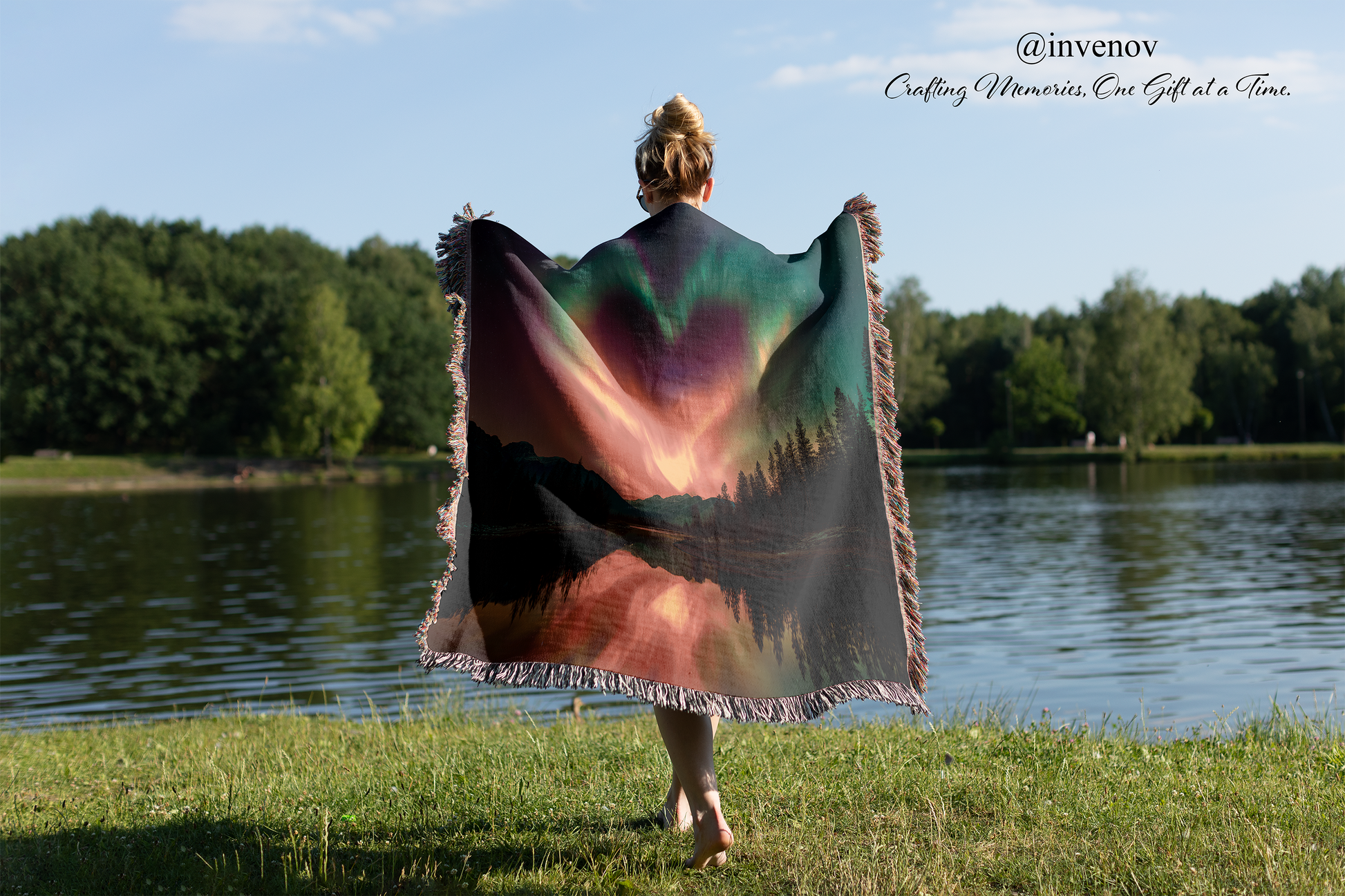 Person holding a colorful blanket with a scenic design by a lake