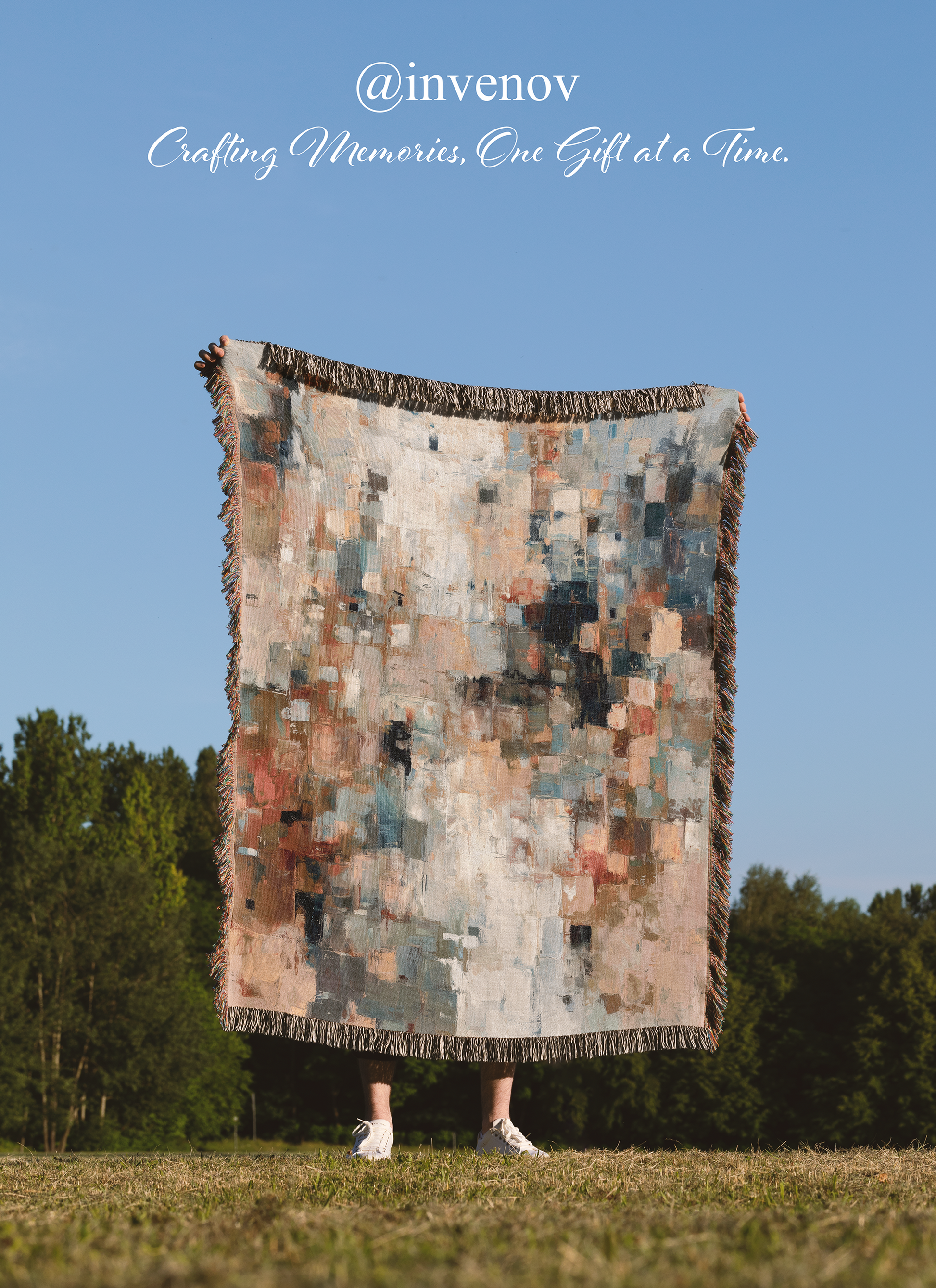 Person holding a large, patterned blanket outdoors with a clear blue sky and trees in the background.