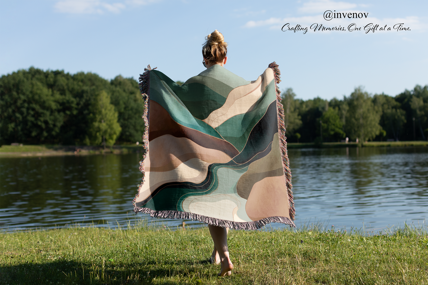 Person holding a colorful blanket by a lake with trees in the background