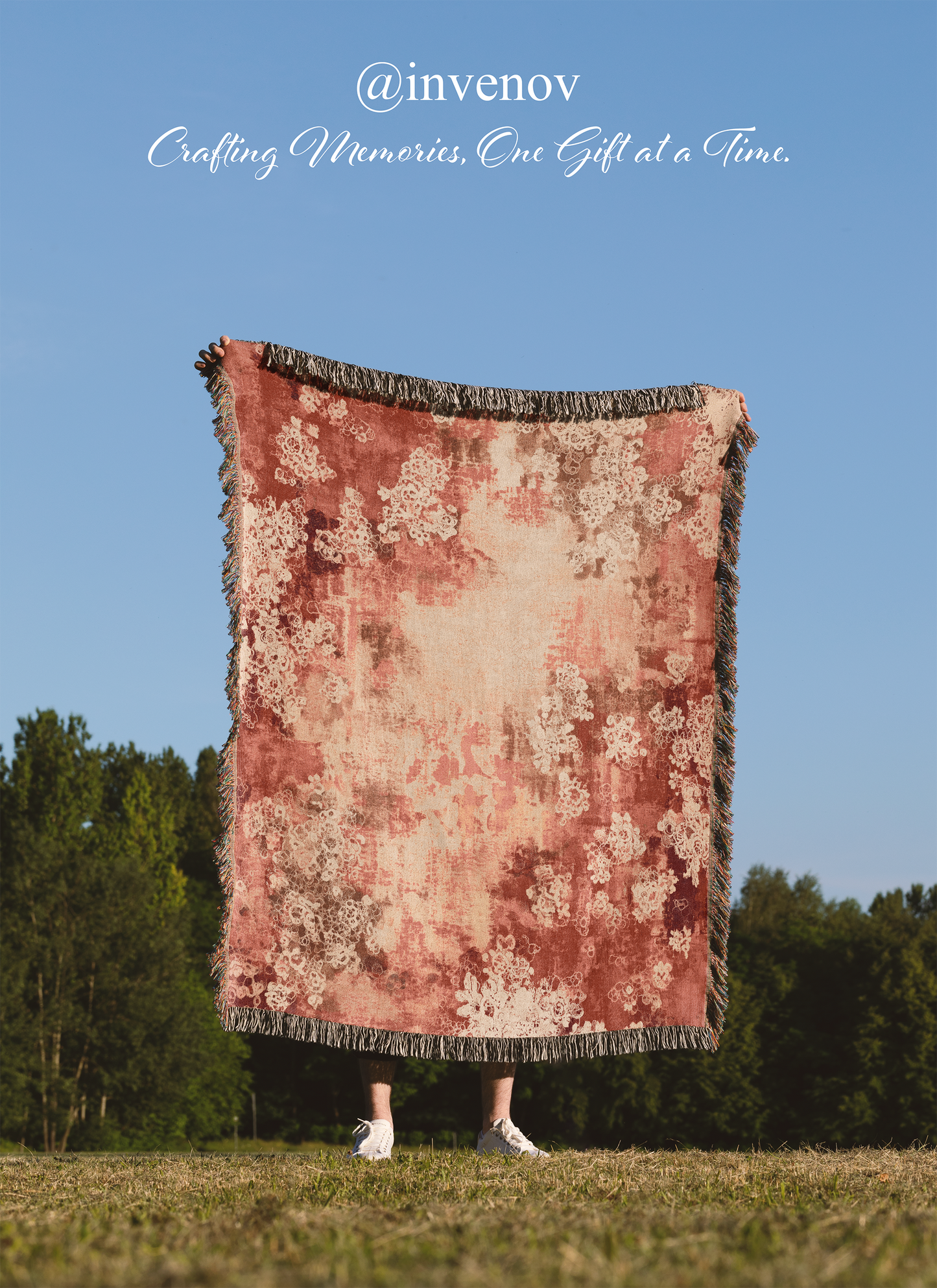Person standing on grass with a floral-patterned blanket draped over them, against a clear blue sky.