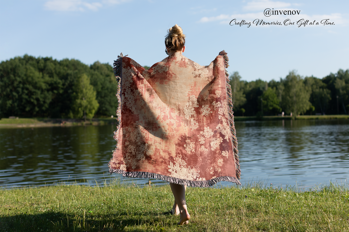 Person holding a floral blanket by a lake with trees in the background