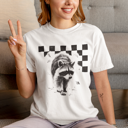 Person wearing a white t-shirt with a raccoon graphic, sitting on a couch.