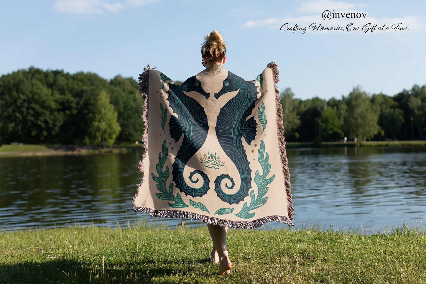 Person holding a decorative blanket by a lake with trees in the background