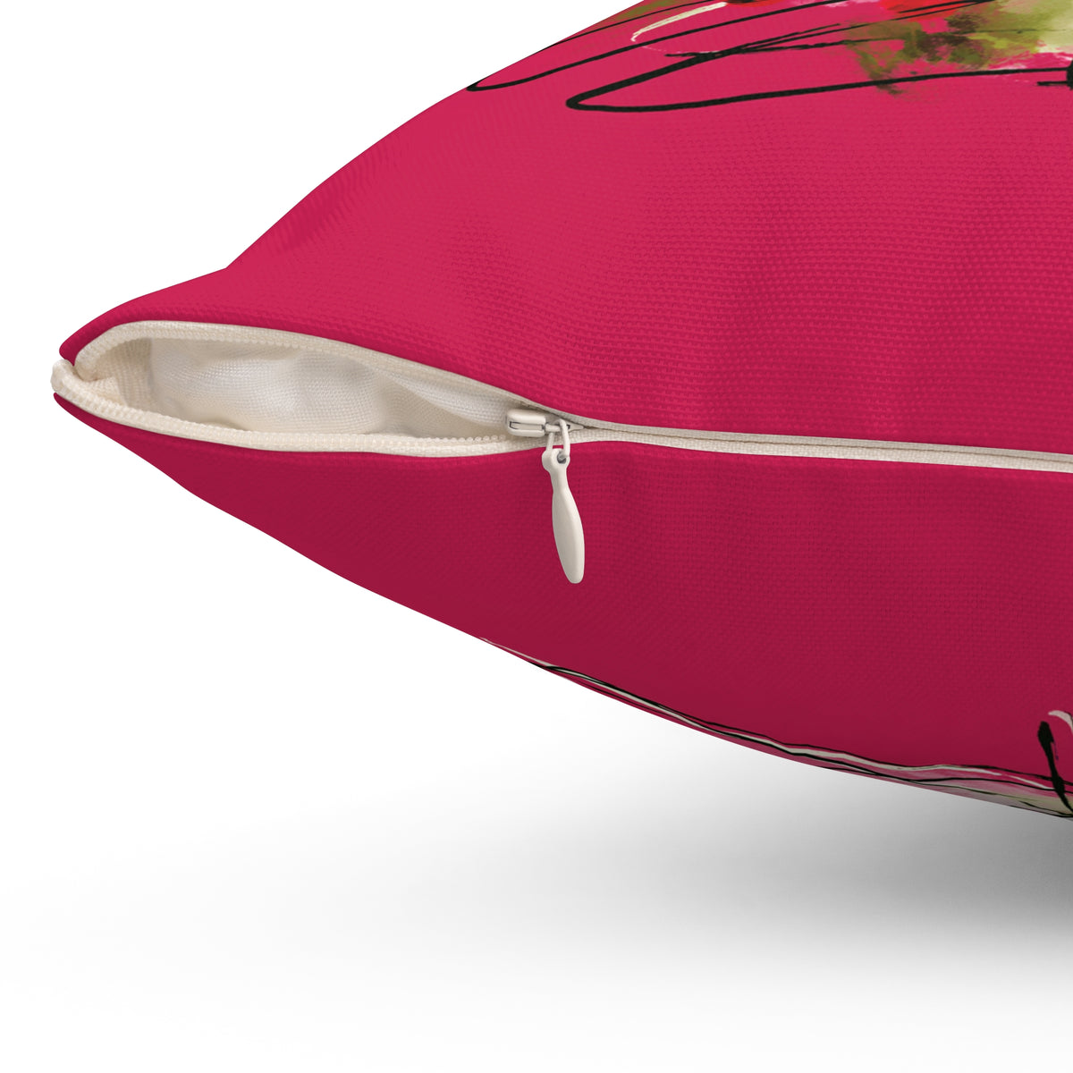 A close-up of a bright pink throw pillow with a partially unzipped corner, showing a cream-colored zipper pull and white inner lining. The pink fabric features a black line-art graphic and a small floral print in the upper right corner.