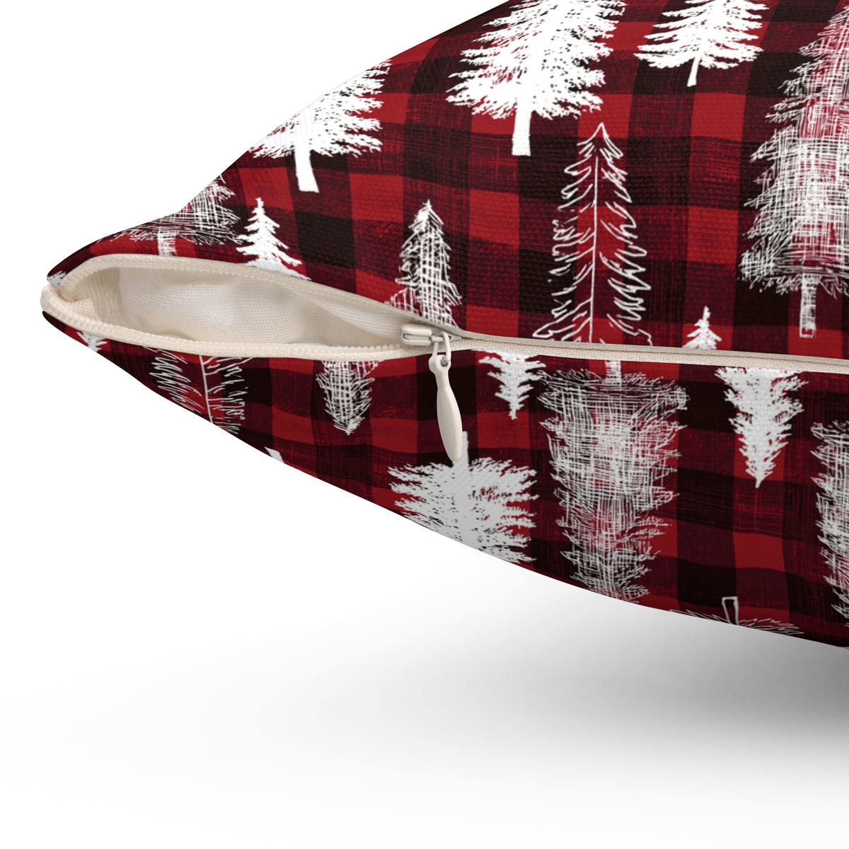 A close-up of a decorative throw pillow with a red and black buffalo plaid pattern overlaid with white pine tree silhouettes, shown with a zipper opening to reveal a light beige interior.