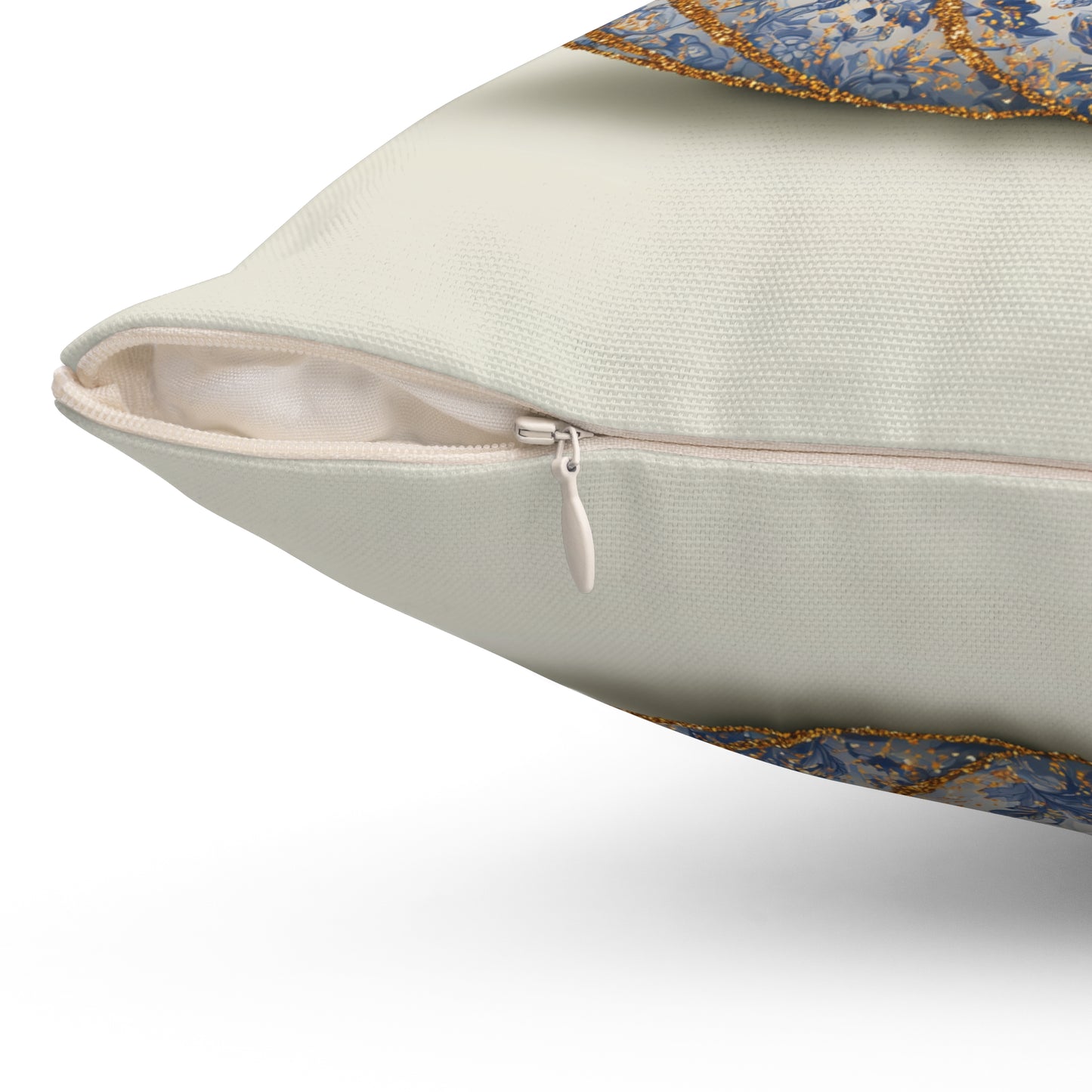 Close-up of a decorative throw pillow showing a cream-colored fabric body, a silver zipper, and blue patterned borders with gold glitter trim on a white background.
