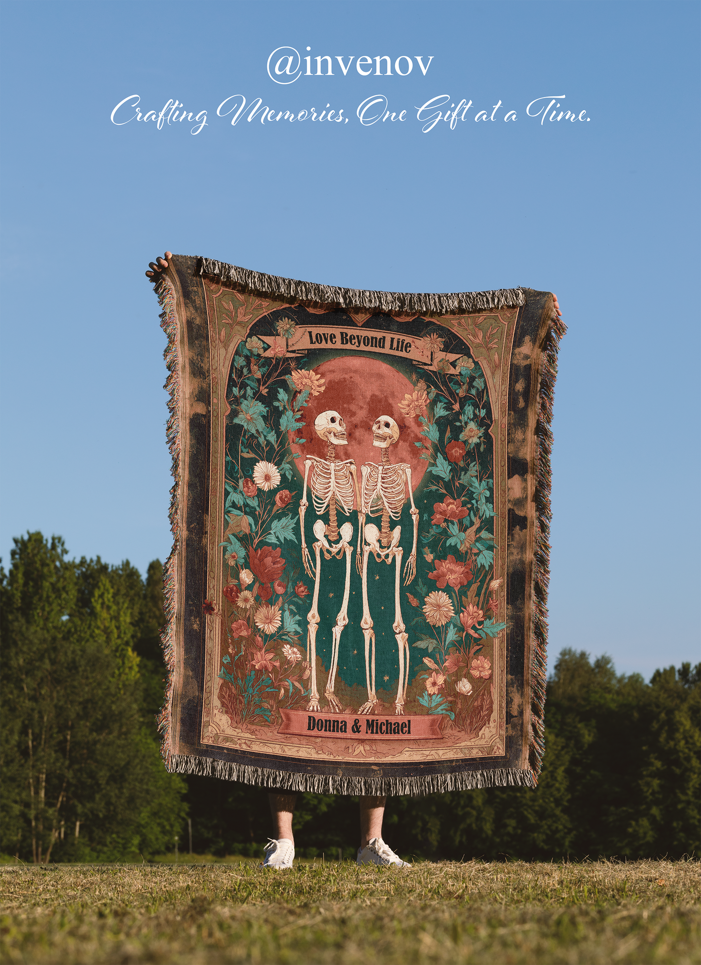 Person holding a decorative blanket with a skeleton design against a blue sky and trees.