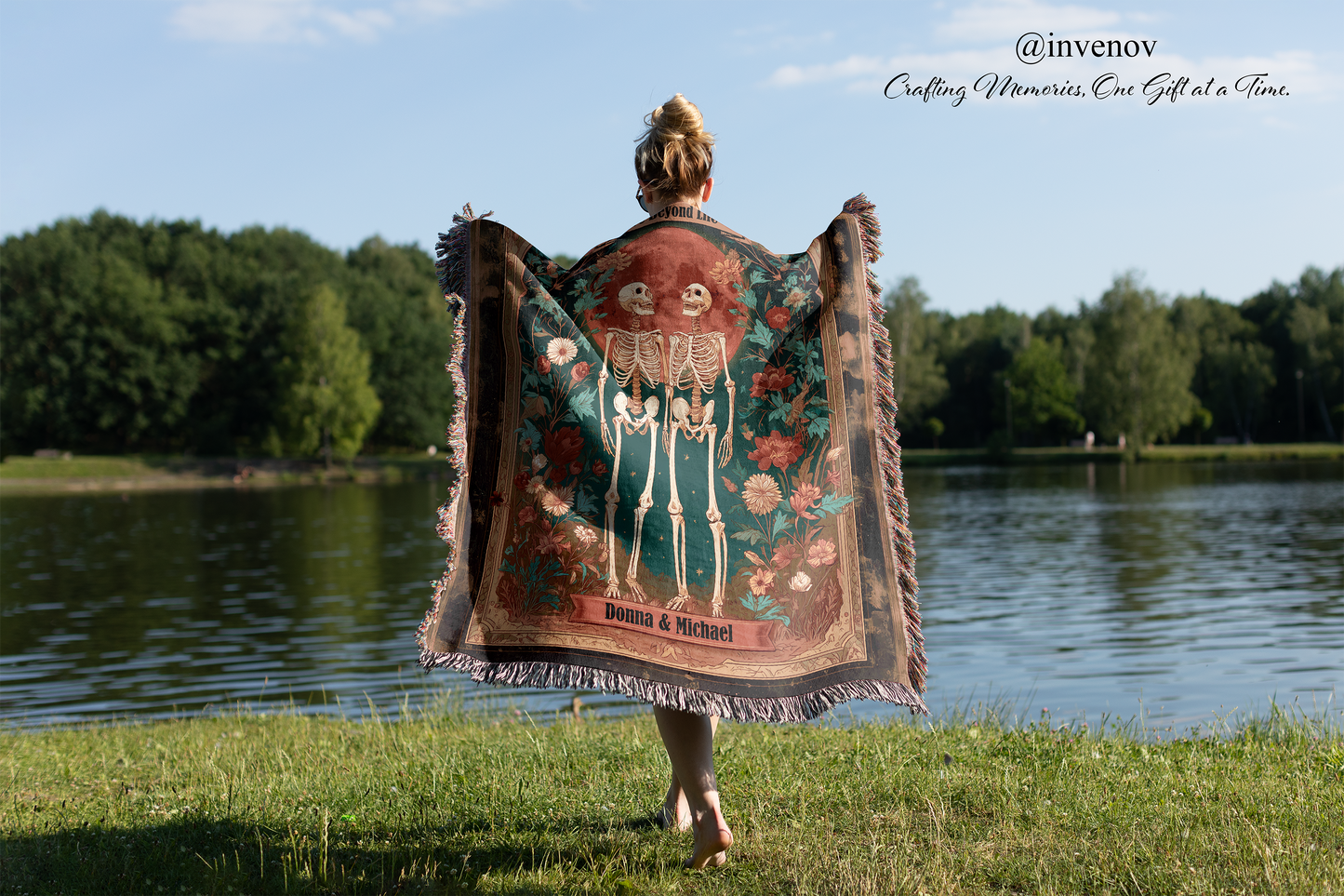 Person holding a decorative blanket with a skeleton design by a lake
