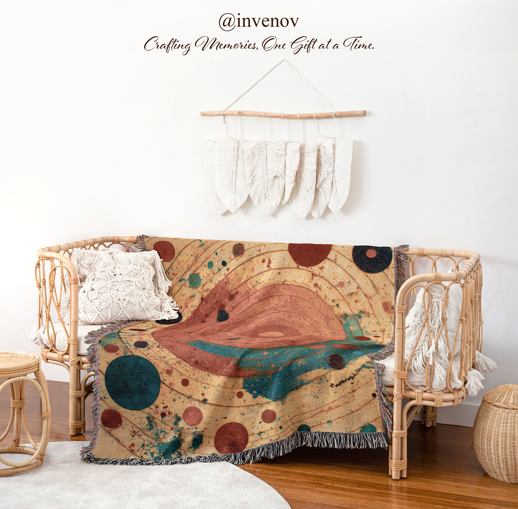 A woven rattan daybed styled in a bohemian room setting, draped with a colorful abstract space-themed throw blanket featuring planets and stars. The room has a white wall decorated with a macrame wall hanging, and a wooden floor.