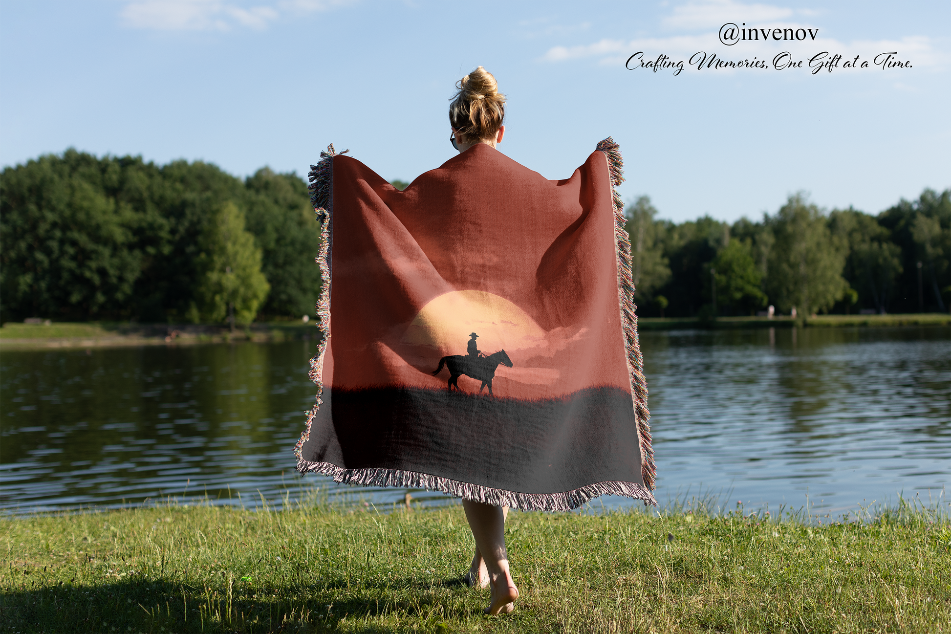 Person holding a blanket with a horse silhouette design by a lake