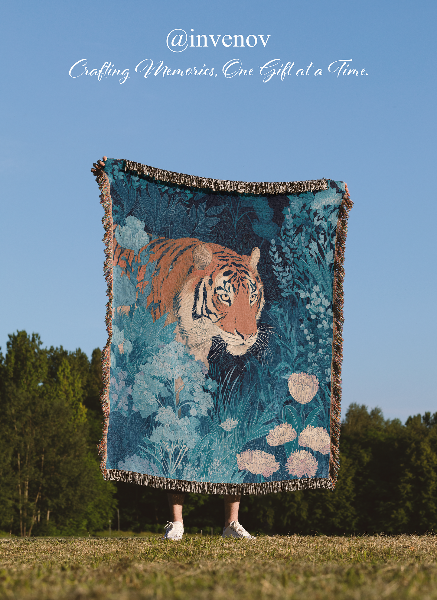 Person holding a tiger-themed blanket with a scenic design against a blue sky.